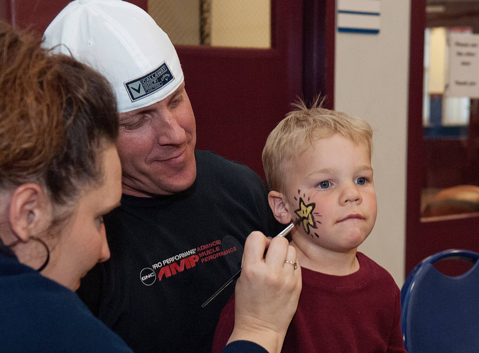 Master Sgt. Joel Harr, 90th Civil Engineer Squadron fire department, looks on as Susan Davis, 90th Force Support Squadron youth program, paints a star on the face of his son Jackson Harr, 3. The Harrs were one of the families taking part in the Warren Youth Center’s festivities marking the end of the Month of the Military Child April 27. (U.S. Air Force photo by R.J. Oriez)