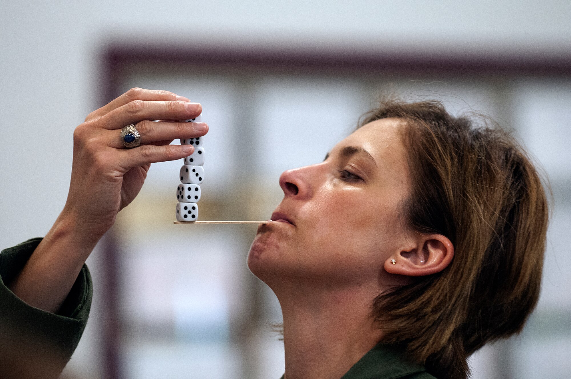 Lt. Col. Catherine Barrington, 90th Operations Support Squadron, attempts to place a sixth die on the stack of dice she is balancing on a stick in a game at the festivities marking the end of the Month of the Military child at Warren’s Youth Center April 27. (U.S. Air Force photo by R.J. Oriez)