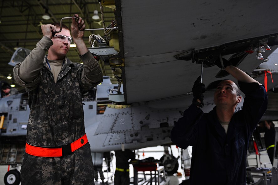 SPANGDAHLEM AIR BASE, Germany – Senior Airman Brian Baker, 52nd Equipment Maintenance Squadron A-10 Thunderbolt II phase technician, left, and Staff Sgt. Francisco Guerrero-Vasquez, 52nd EMS crash recovery team supervisor, work together to remove an aileron bracket on the wing of an A-10 during a phase inspection in Hangar 2 here May 4. The phase inspections are separated into two categories. During a phase 1 inspection, the 52nd EMS Maintenance Flight members examine each A-10 after every 500 flying hours, and phase 2 inspections are performed every 1,000 flying hours. These inspections allow the Airmen to check for deficiencies and perform preventative maintenance to ensure the aircraft is safe and operational for flight. (U.S. Air Force photo by Airman 1st Class Matthew B. Fredericks/Released)