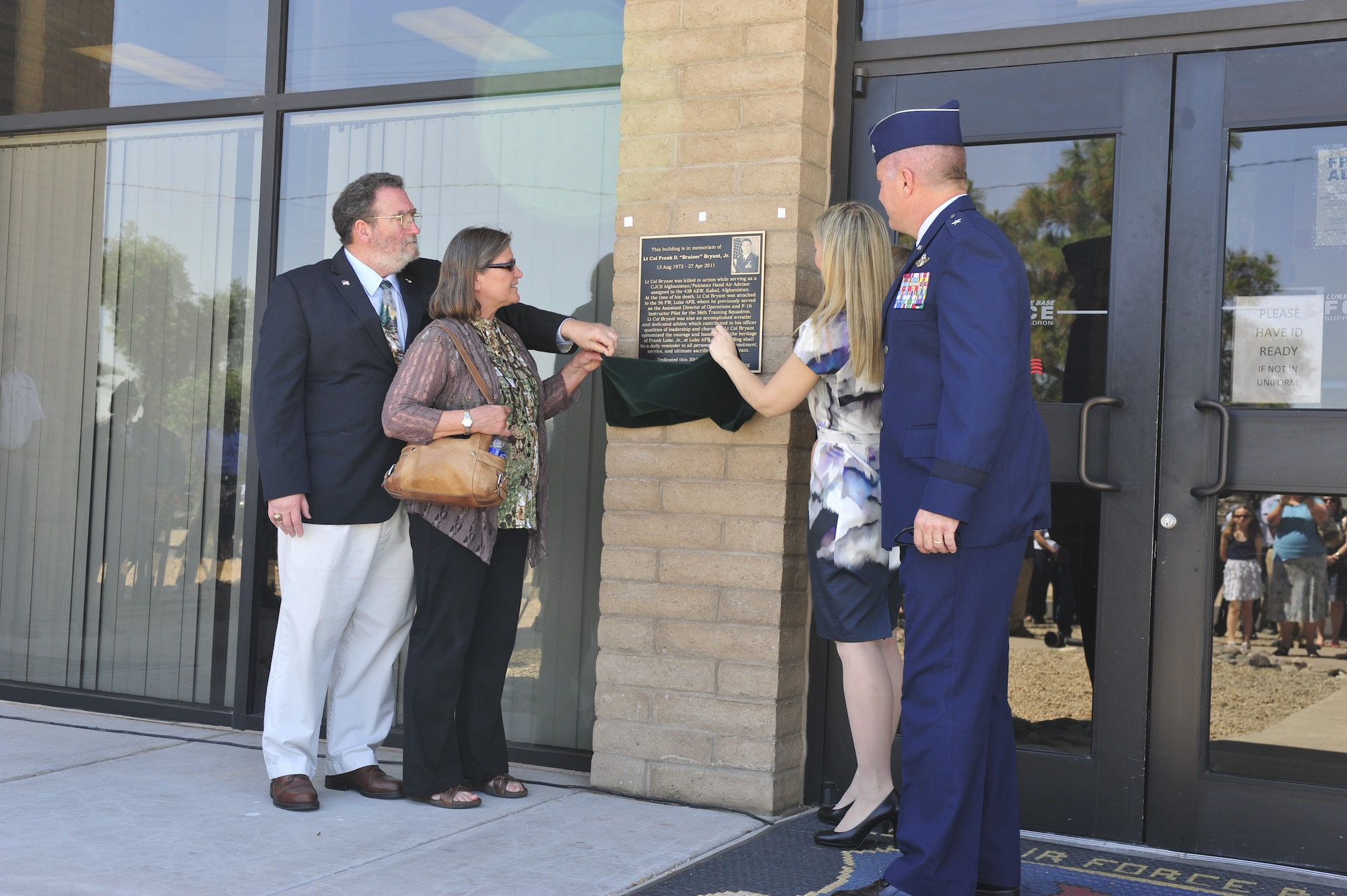 Father, Frank Sr.; mother, Patricia; and wife, Janice; of Lt. Col. Frank Bryant Jr., unveil the memorial plaque placed at the entrance of the fitness center Monday at Luke Air Force Base. The plaque details the life and career of Bryant, explaining how he was killed in action in Afghanistan.   (U.S. Air Force photo by Staff Sgt. Jason Colbert)