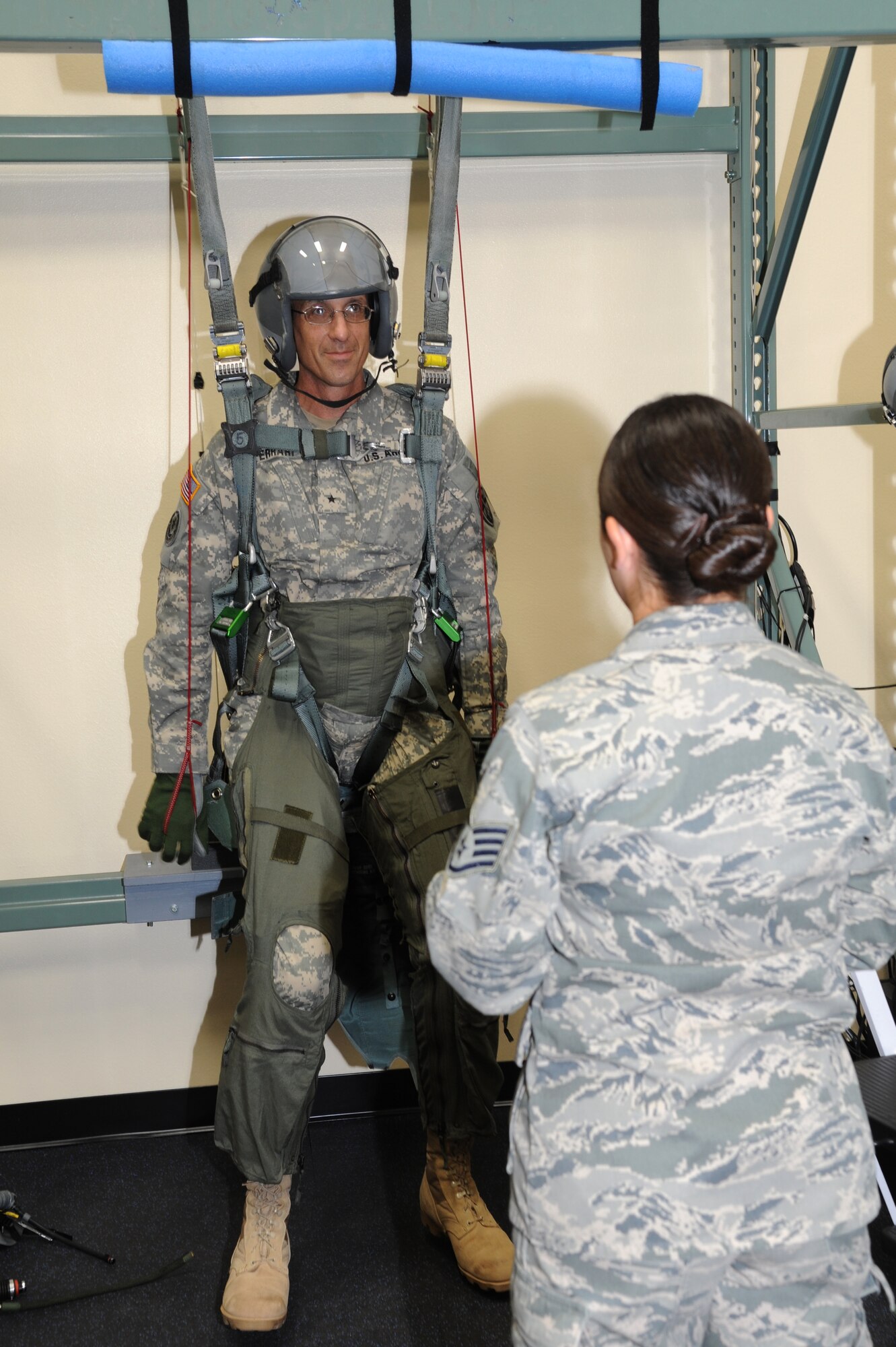 U.S. Army Brig. Gen. John Ferrari, White Sands Missile Range commanding general, receives F-16 egress training April 24 from Staff Sgt. Veronica Armstrong, 56th Operations Support Squadron NCO-in-charge aircrew flight equipment continuation trainer, before his flight in the F-16 with the 310th Fighter Squadron. (U.S. Air Force photo by Senior Airman Sandra Welch)