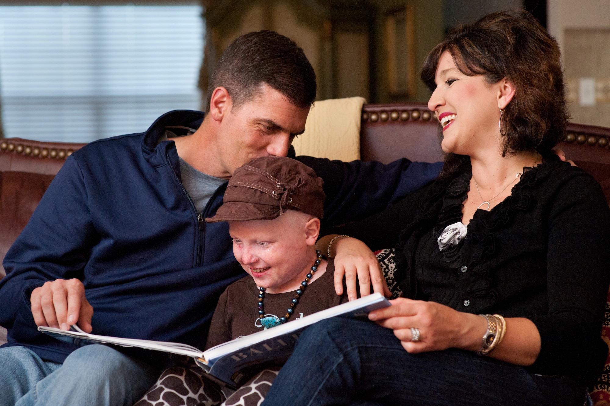 Col. Dwight Sones, left, 60th Air Mobility Wing commander, places a gentle kiss on the head of his daughter, Karina, 11, while he and his wife, Dana, read one of their family's favorite books. Karina had acute lymphocytic leukemia and was once helped by a marrow donor. Travis will host a bone marrow drive from May 14 to 18 at various locations on base. (U.S. Air Force photo/Ken Wright)