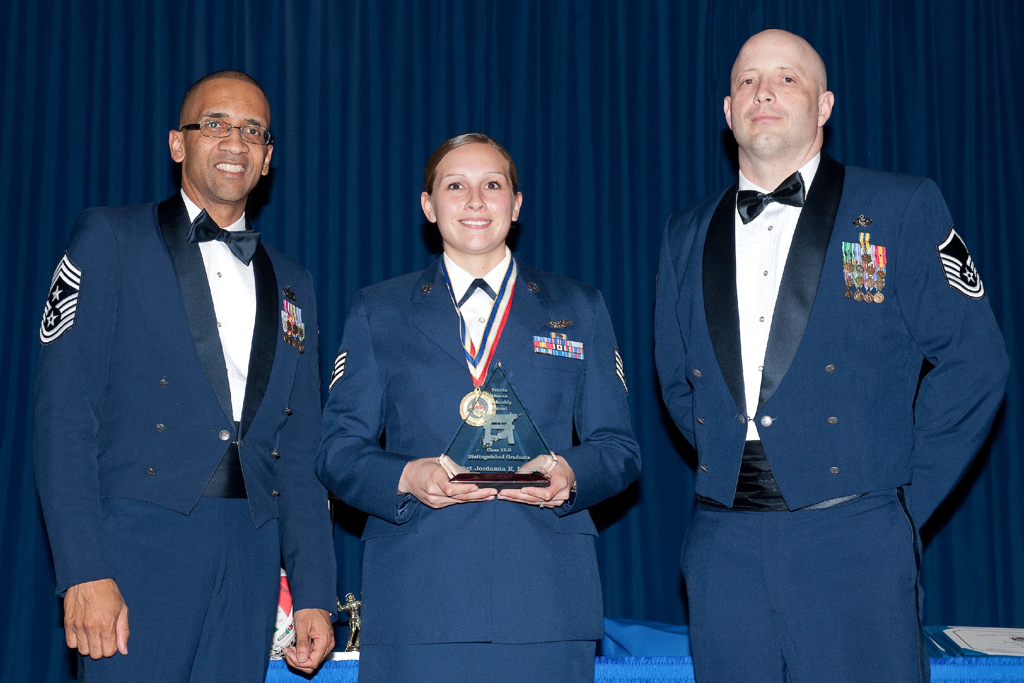 YOKOTA AIR BASE, Japan -- Staff Sgt. Jordanna Lozano (center), 36th Airlift Squadron, is awarded the Distinguished Graduate Award during the Airman Leadership School Class 12-Delta graduation ceremony at Yokota Air Base, Japan, May 3, 2012. Chief Master Sgt. Ronald Draper (left), 374th Airlift Wing, and Master Sgt. Robert Poole (right), 374th Civil Engineer Squadron, representatives of the Civil Engineering Association, presented the award to Lozano during the ceremony. (U.S. Air Force photo/Osakabe Yasuo)