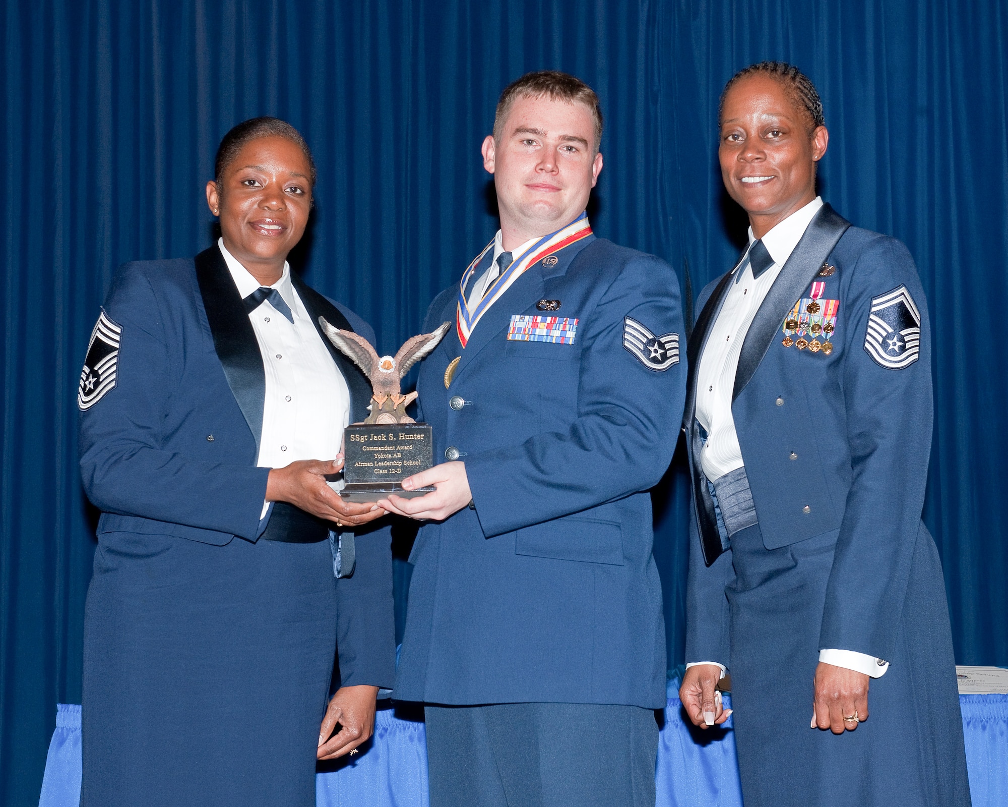 YOKOTA AIR BASE, Japan -- Staff Sgt. Jack Hunter (center), 730th Air Mobility Squadron, awarded the Commandant Award during the Airman Leadership School Class 12-Delta graduation ceremony at Yokota Air Base, Japan, May 3, 2012. Chief Master Sgt. Sonya Mayo (left) and Senior Master Sgt. Nanette Klingaman (right), both from the 374th Force Support Squadron, representatives of the Yokota's Chief Group, presented the award to Hunter during the ceremony. (U.S. Air Force photo/Osakabe Yasuo)