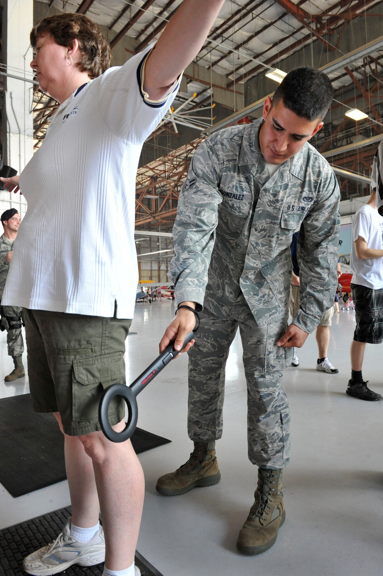 U.S. Air Force Airman 1st Class Oscar Gonzalez, 20th Civil Engineer Squadron heating, ventilation and air conditioning apprentice, scans a woman entering the Shaw Air Expo with a hand-held metal detector at Shaw Air Force Base, S.C., May 5, 2012. More than 20 security force augmenties from different squadrons of the 20th Fighter Wing performed security checks at the entrance of the Shaw Air Expo during the first day of the air show. The Shaw Air Expo will be held both May 5 and 6 and is free to the general public. (U.S. Air Force photo by Senior Airman Amber E. N. Jacobs/Released) )