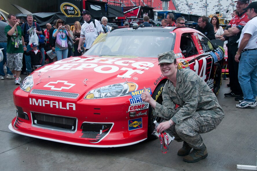 Senior Airman Amanda Winkler gives a thumbs up to NASCAR driver Tony Stewart's car at Bristol Motor Speedway prior to the Food City 500 NASCAR race on March 18, 2012.  Amn Winkler was one of four airmen from the McGhee Tyson Air National Guard Base, Tennessee who were invited to sing the National Anthem prior to the race