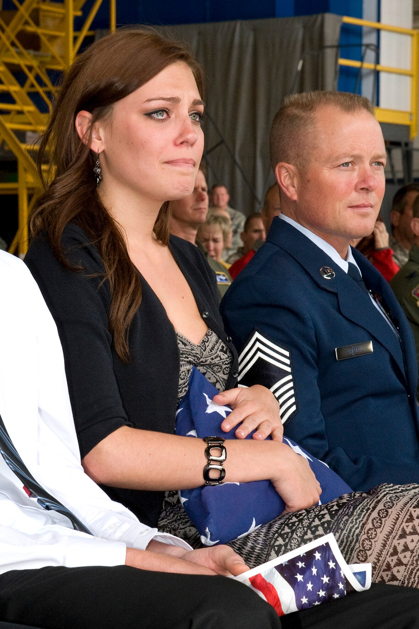 An emotional Kyler Burch, daughter of 302nd Airlift Wing Command Chief Master Sgt.  Suzette Cherry holds the flag her mother presented to her during the chief’s retirement ceremony as Cherry’s husband, Chief Master Sgt. Robert Cherry looks on.  “You have been with me through it all -- every promotion, every tech school, every TDY. Thank you for your support,” said Cherry to Burch as she handed over her retirement flag. (U.S. Air Force photo/Craig Denton)