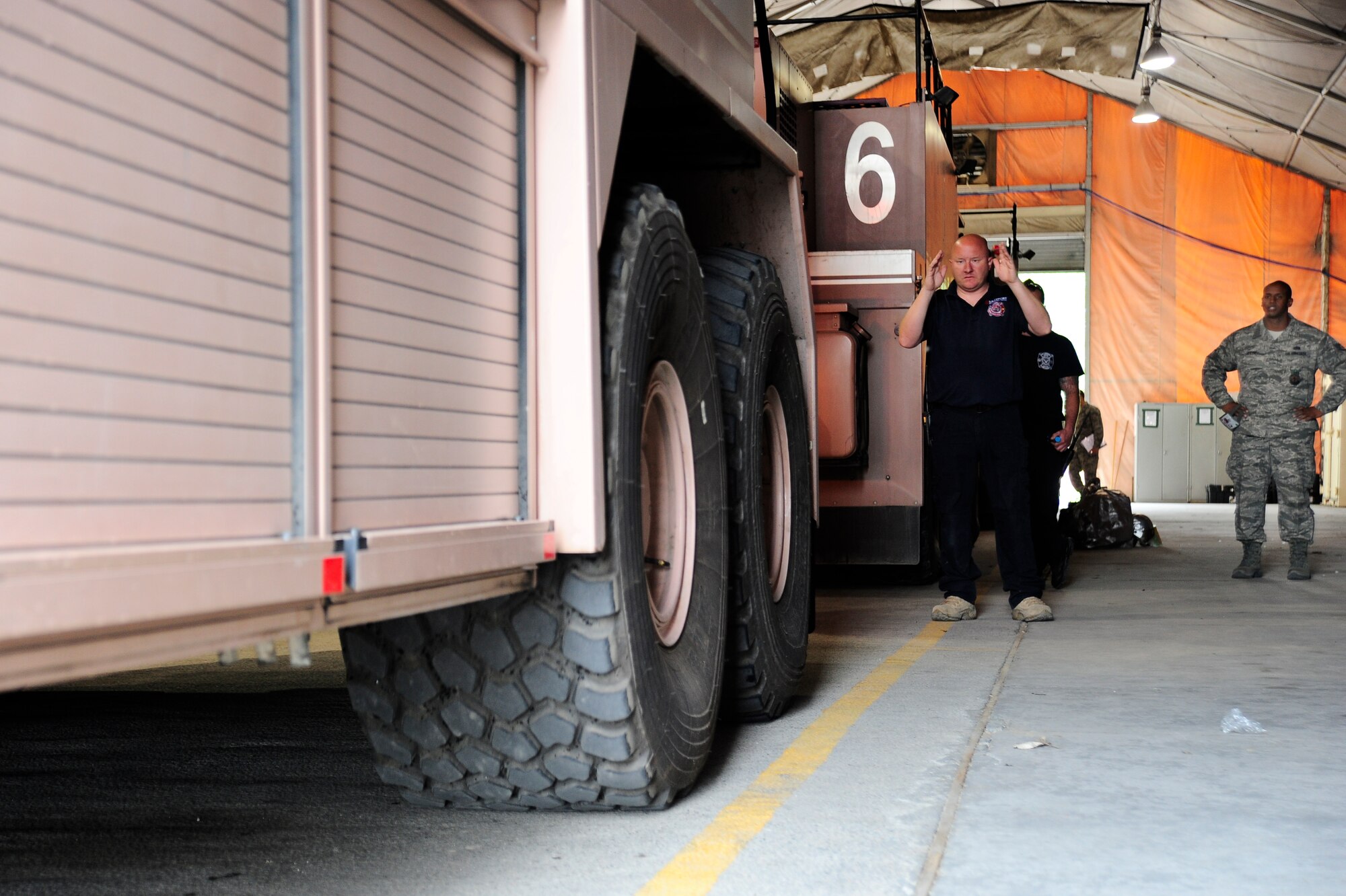 Mark Williams marshals a T-300 aircraft fire apparatus into fire station one, while Staff Sgt. Tony Greene observes April 27, 2012, at the Transit Center at Manas, Kyrgyzstan. Williams is a Sally Port Emergency Services contractor and is originally from Kimble, Neb. Greene is a 376th Expeditionary Civil Engineer Squadron fire fighter deployed here from Patrick Air Force Base, Fla. (U.S. Air Force photo/Staff Sgt. Angela Ruiz)
