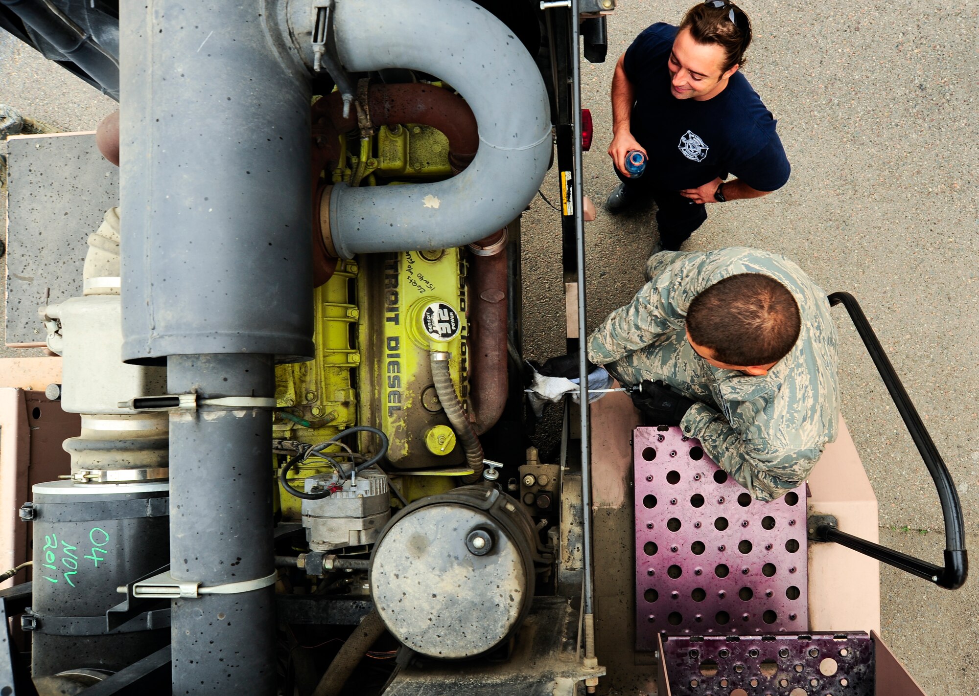 John O'Brien and Airman 1st Class Dominic Florini check the fluids in a T-300 aircraft fire apparatus April 17, 2012, at the Transit Center at Manas, Kyrgyzstan. O'Brien is a Sally Port Emergency Services contractor originally from Baumount, Texas. Florini is a 376th Expeditionary Civil Engineer Squadron fire fighter deployed here from Barksdale Air Force Base, La. (U.S. Air Force photo/Staff Sgt. Angela Ruiz)