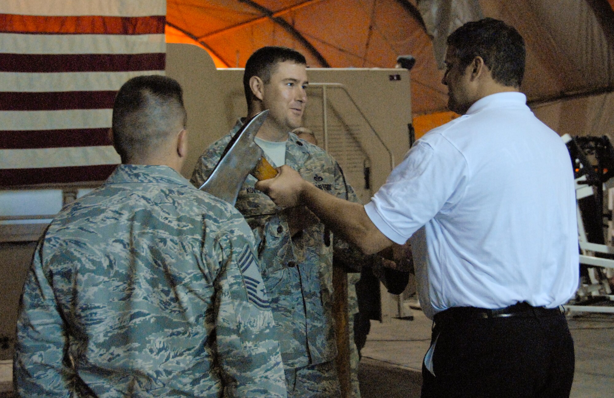 Lt. Col. Matthew Kovich, 376th Expeditionary Civil Engineer Squadron commander, receives the fire ax from George Parker III, Sally Port Fire Emergency Services fire chief, and prepares to pass it to Chief Master Sgt. Stephen Groszek, at the Transit Center at Manas, Kyrgyzstan, during a shift change ceremony April 30, 2012. The passing of the fire ax symbolizes the transfer of authority from civilian to Air Force control. (U.S. Air Force photo/Senior Airman Lynsie Nichols)