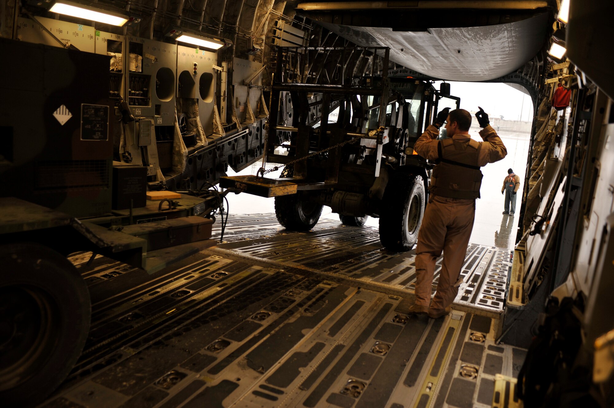 Airman 1st Class Brian Lewment directs the unloading of a generator from a C-17 aircraft during the 1st Infantry Division’s Relief in Place/Transfer of Authority at Bagram Airfield, Afghanistan, March 20, 2012. Lewment is a loadmaster with the 816th Air Expeditionary Squadron and is deployed from Charleston Air Force Base, S.C. Communication was key in the execution of the RIP/TOA, a joint operation that allowed the 1st Infantry Division to successfully settle into it’snew responsibilities working with the Afghan National Security Forces. (U.S. Air Force photo/Airman 1st Class Ericka Engblom)