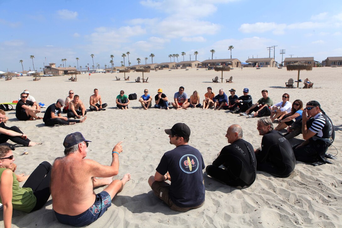 Participants with the Jimmy Miller Memorial Foundation gather in a meet-and-greet circle before hitting the water for a surf session, part of ocean therapy.  Ocean therapy facilitates improved self-esteem for service members dealing with mental and physical illness.