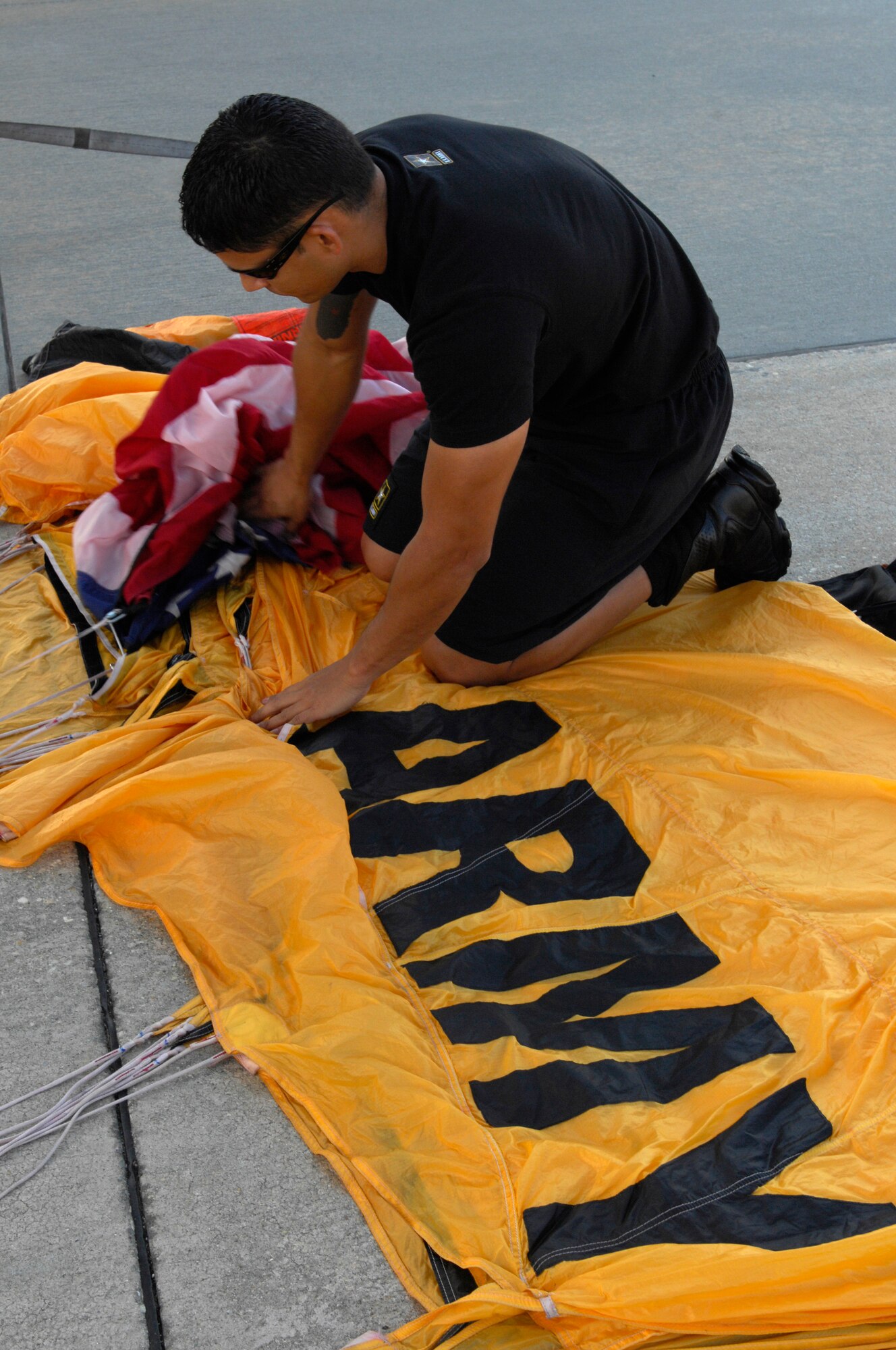 U.S. Army Sgt. John Lopez, U.S. Army Parachute Team black team, prepares his parachute and attaches the American flag to it before the U.S. Army Golden Knights’ performance during 2012 Shaw Air Expo held at Shaw Air Force Base, S.C., May 6, 2012. The Golden Knights start the expo off every morning with a skydive carrying the U.S. flag as they descend at show center during the national anthem. (U.S. Air Force photo by Airman 1st Class Krystal M. Jeffers/Released)