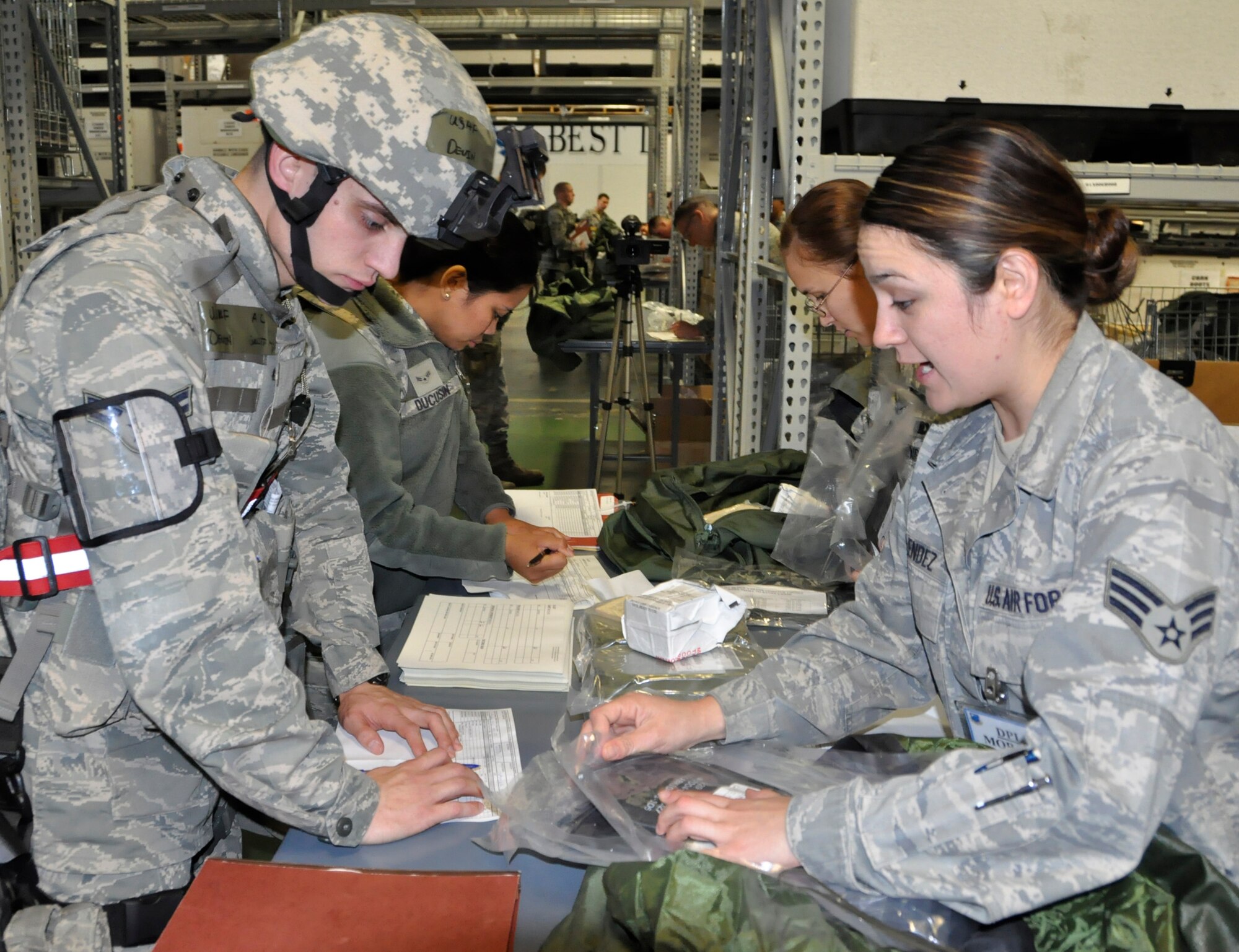 Senior Airman Yuri Melendez, from the 627th Logistics Readiness Squadron, explains issued equipment to Airman 1st Class Devin Briton, from the 446th Security Forces Squadron. Both active duty and Reserve Airmen processed through a deployment line for a fly-away operational readiness exercise May 6. More than 300 Airmen from various squadrons travelled on C-17 Globemasters to an undisclosed deployed location where they will simulate 24-hour operations in a combat zone. This exercise is in preparation for the operational readiness inspection set for October. (U.S. Air Force photo/Staff Sgt. Rachael Garneau)