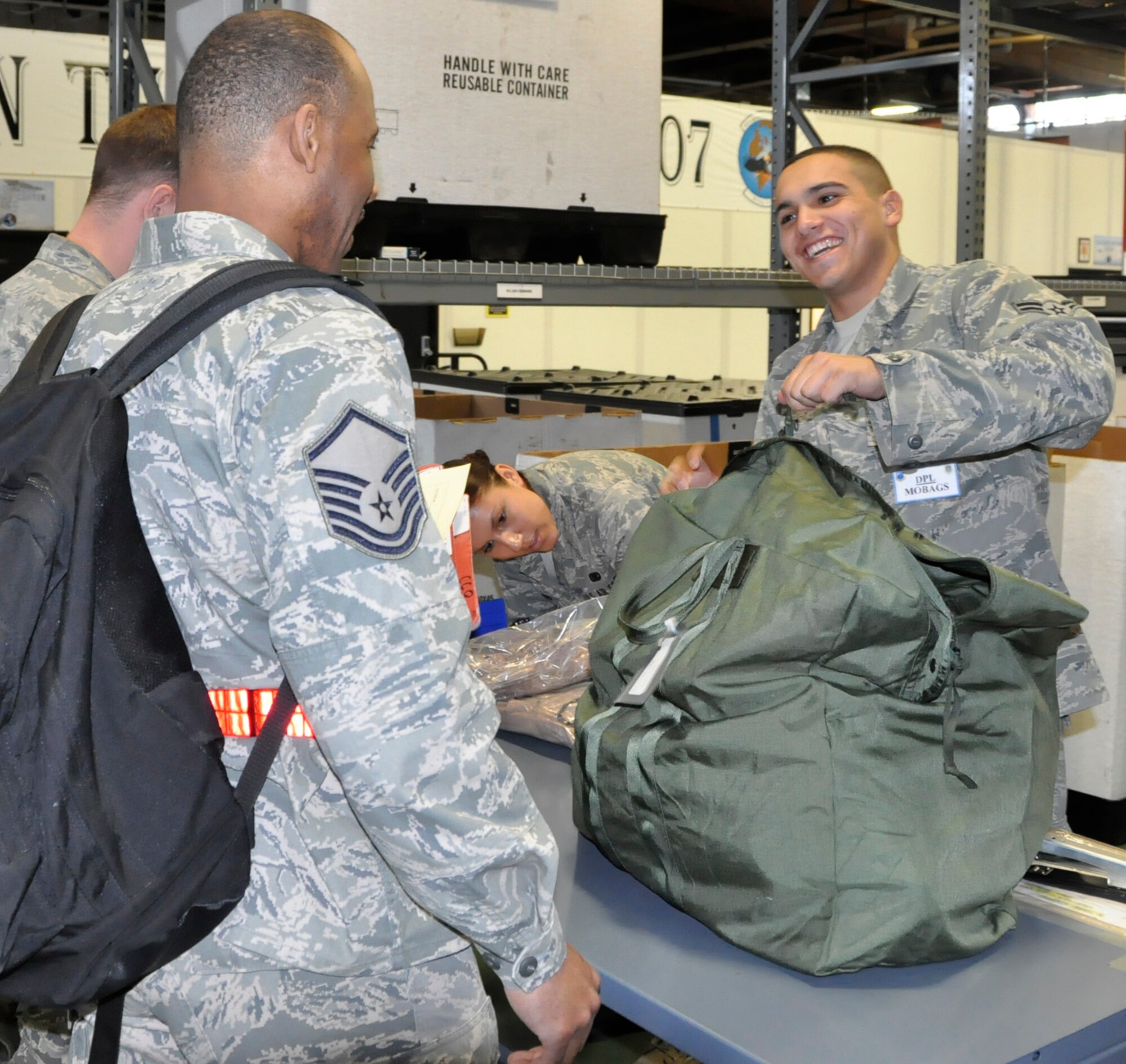 Airman 1st Class Nicolas Mercado, 627th Logistics Readiness Squadron, issues a mobility bag to Master Sgt. Dwayne Williams, 446th Force Support Squadron. Both active duty and Reserve Airmen processed through a deployment line for a Team McChord fly-away operational readiness exercise May 6. More than 300 Airmen from various squadrons travelled on C-17 Globemasters to an undisclosed deployed location where they will simulate 24-hour operations in a combat zone. This exercise is in preparation for the operational readiness inspection set for October. (U.S. Air Force photo/Staff Sgt. Rachael Garneau)