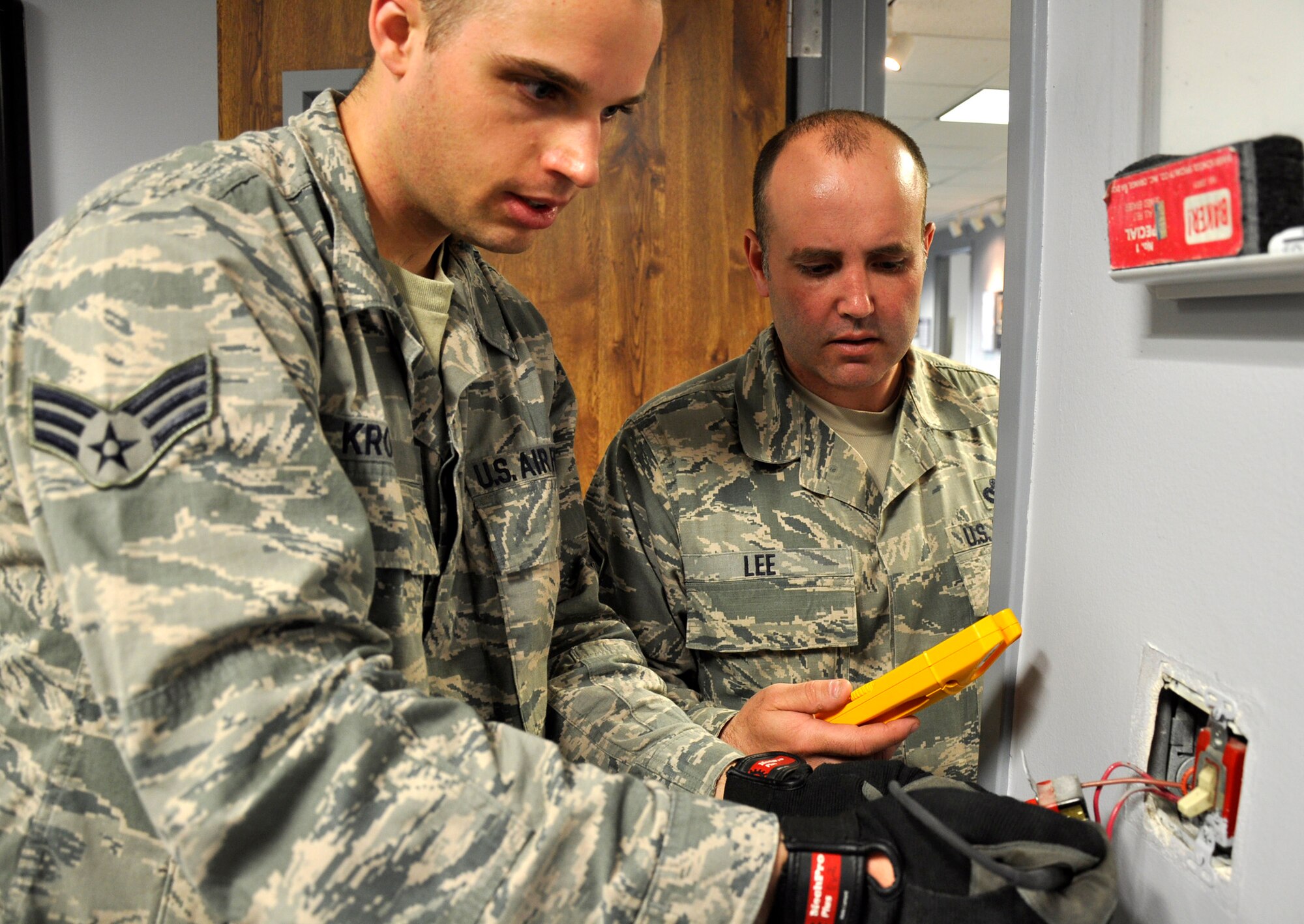 Senior Airman Ron Krotzer, a 446th CES electrician apprentice, takes a reading with a voltmeter from an electrical outlet.  He works under the supervision of his trainer, Master Sgt. Dwayne Lee, 446th CES electrician, who has been a journeyman electrician with the International Brotherhood of Electrical Workers Union Local 76 for the past seven years.  Performing the work in house both saves money and allows the apprenctice airmen to get valuable on-the-job training they need to become fully qualified. (U.S. Air Force photo by Master Sgt. Jake Chappelle)