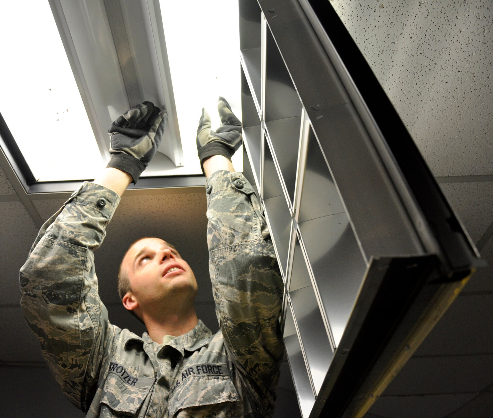 Senior Airman Ron Krotzer, a 446th CES electrician apprentice, performs upgrades on the lighting system in Building 1210.  Krotzer works under the supervision of his trainer, Master Sgt. Dwayne Lee, 446th CES electrician, who has been a journeyman electrician with the International Brotherhood of Electrical Workers Union Local 76 for the past seven years.  Performing the work in house both saves money and allows the apprenctice airmen to get valuable on-the-job training they need to become fully qualified. (U.S. Air Force photo by Master Sgt. Jake Chappelle)