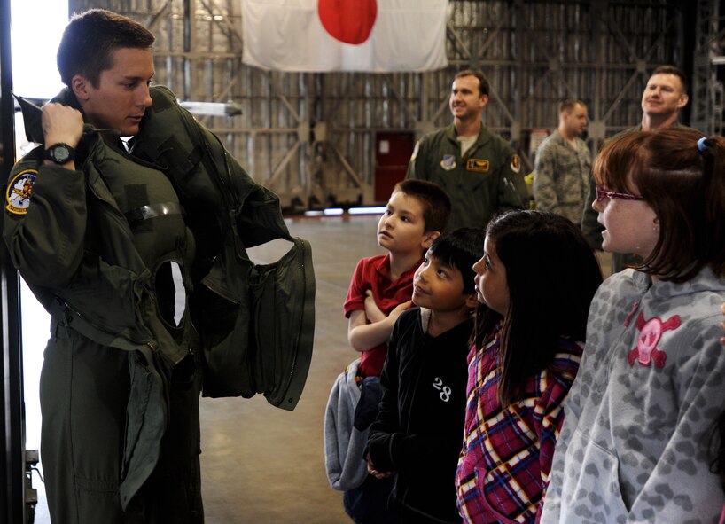 U.S. Air Force Capt. Josh Masopust, 14th Fighter Squadron electronic combat pilot, demonstrates the proper way to wear in-flight equipment to Sollars Elementary School’s third grade students in Hangar 911 at Misawa Air Base, Japan, May 3, 2012. The static display served as an educational field trip and gave the students the chance to have face-to-face conversations with active servicemembers. (U.S. Air Force photo/Airman Kenna Jackson/Released) 
