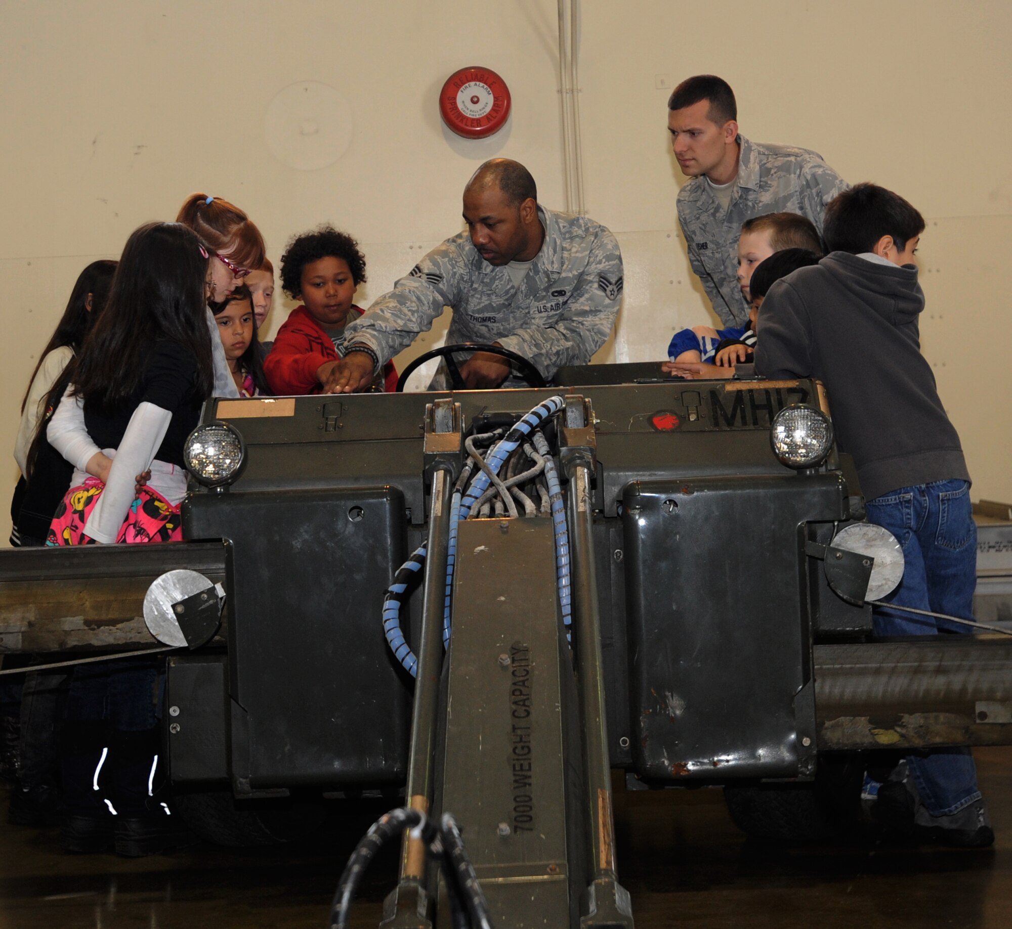 U.S. Air Force Senior Airman Kasaun Thomas, 35th Maintenance Group, squadron lead crew member, demonstrates how to work a MHU-83 bomb lift truck to Sollars Elementary School’s third grade students in Hangar 911 at Misawa Air Base, Japan, May 3, 2012. Over 100 students visited the static display, where they were given the opportunity to ask questions and learn what the wing is capable of. (U.S. Air Force photo by Airman Kenna Jackson/Released)