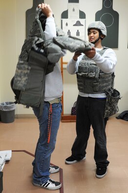 Son of U.S. Navy Senior Chief Petty Officer Samuel Garana, right, Patrol and Reconnaissance Force 7th Fleet (CTF-72), helps the son of retired Petty Officer 1st Class Charlie Baroy put on a personal body armor plate carrier vest during a visit to the small arms range at Misawa Air Base, Japan, May 4, 2012. Students from Edgren High School's Junior Reserve Officer Training Corps visited the small arms range to learn about some of the training their parents must receive before deploying and the weapons and equipment they use downrange. (U.S. Air Force photo/Airman 1st Class Kia Atkins/Released) 
