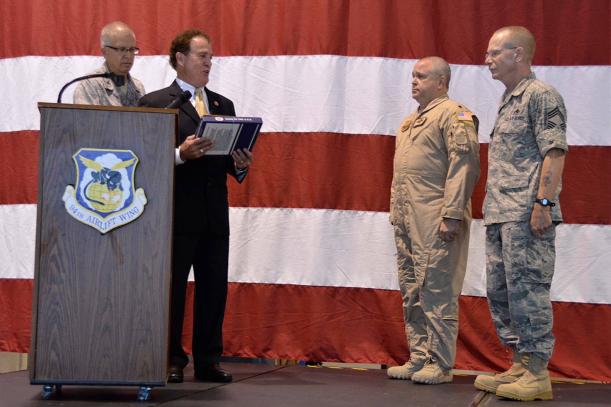 Congressman Phil Gingrey, Georgia’s 11th District, presents a flag flown on Sept. 11, 2001 to Lt. Col. Thomas Moffatt of the 700th Airlift Squadron and Chief Master Sgt. Stephen Hogan, 94th Maintenance Squadron, during a recent deployment departure ceremony at Dobbins Air Reserve Base, Ga. Over 100 94th Airlift Wing members recently deployed to the Middle East to provide personnel and cargo delivery using C-130 aircraft. (U.S. Air Force photo/Master Sgt. James Branch)