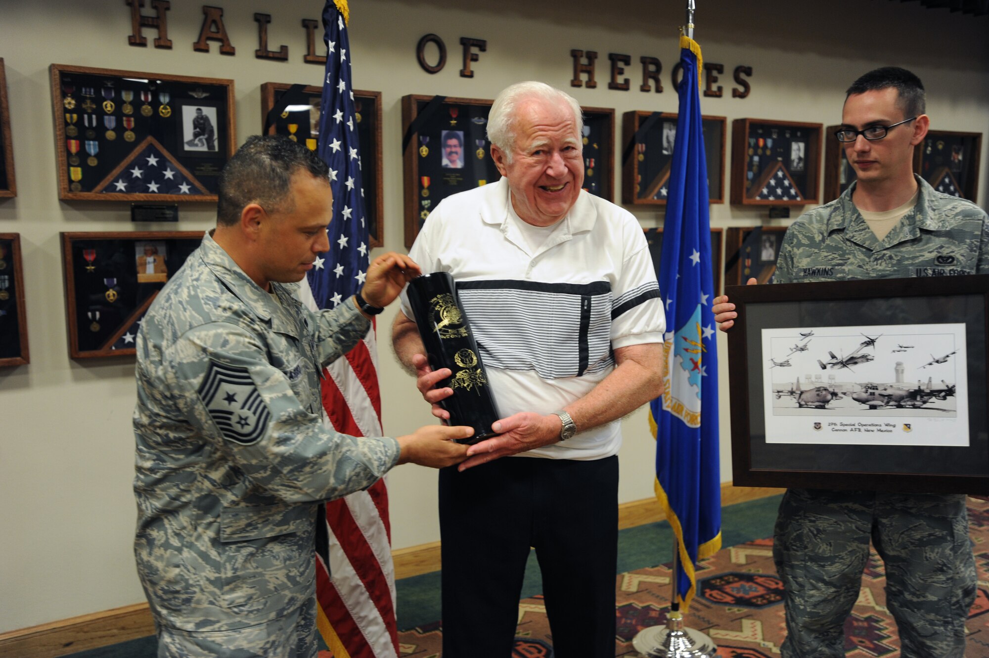 U.S. Air Force Chief Master Sgt. Matthew Caruso, 27th Special Operations Wing command chief, and Staff Sgt. Dustin Hawkins, 27th Special Operations Civil Engineer Squadron electrical power production journeyman, award John Carlson during a Hall of Heroes recognition ceremony at Cannon Air Force Base, N.M., April 26, 2012. Carlson was the twenty-first person to be inducted into the hall of heroes, a program that honors service members who have made great sacrifice while serving their country. (U.S. Air Force photo by Senior Airman Jette Carr)