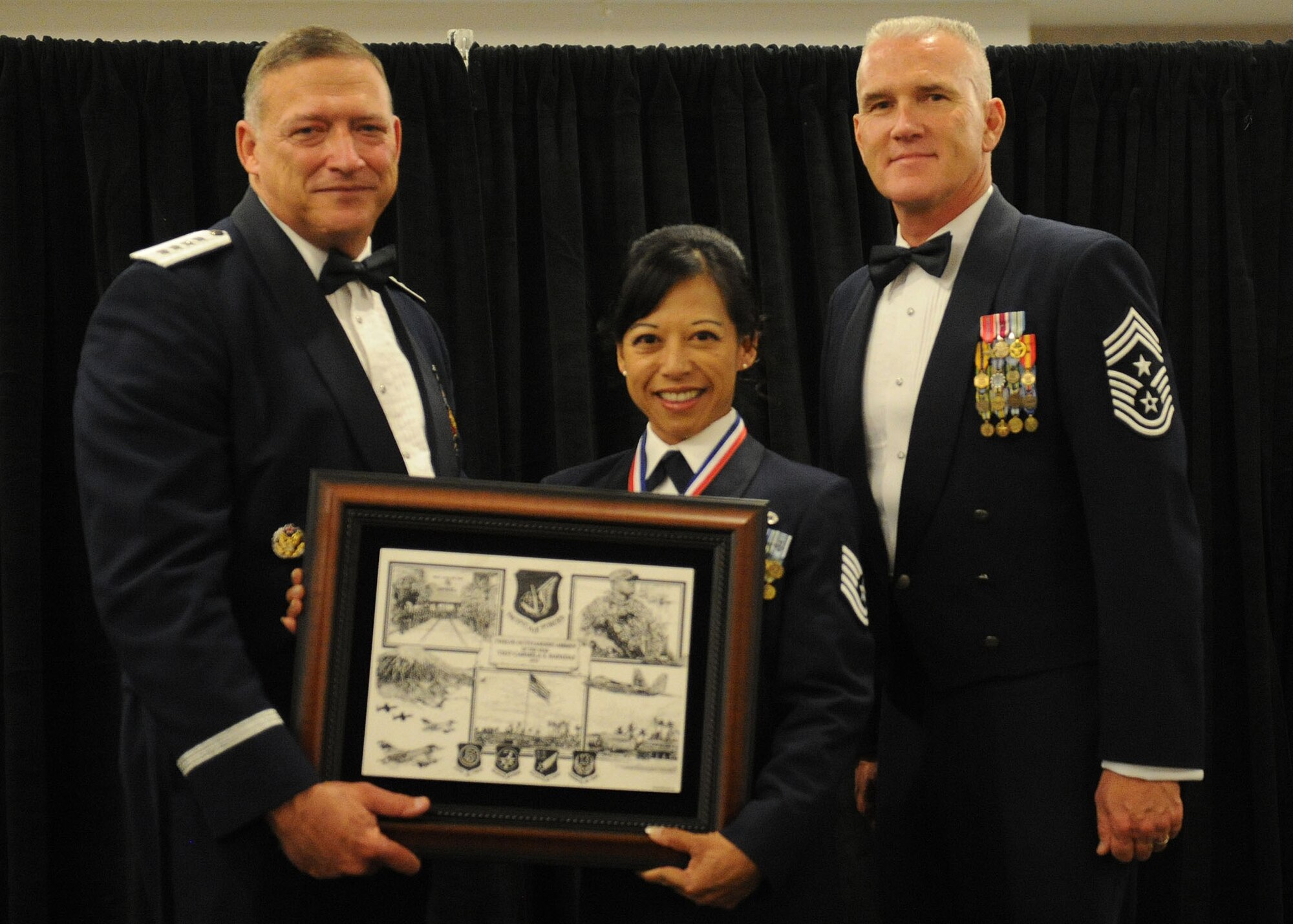 Pacific Air Forces commander Gen. Gary North and Chief Master Sgt. Brooke McLean, PACAF command chief, present Tech. Sgt. Carmela Rapadas, protocol noncommissioned officer in charge from the 254th Force Support Squadron, Guam Air National Guard, Guam, with PACAF Outstanding Airman of the Year honors at the Tradewinds Enlisted Club, Joint Base Pearl Harbor-Hickam, Hawaii, April 27, 2012. (U.S. Air Force photo/Tech. Sgt. Jerome S. Tayborn)