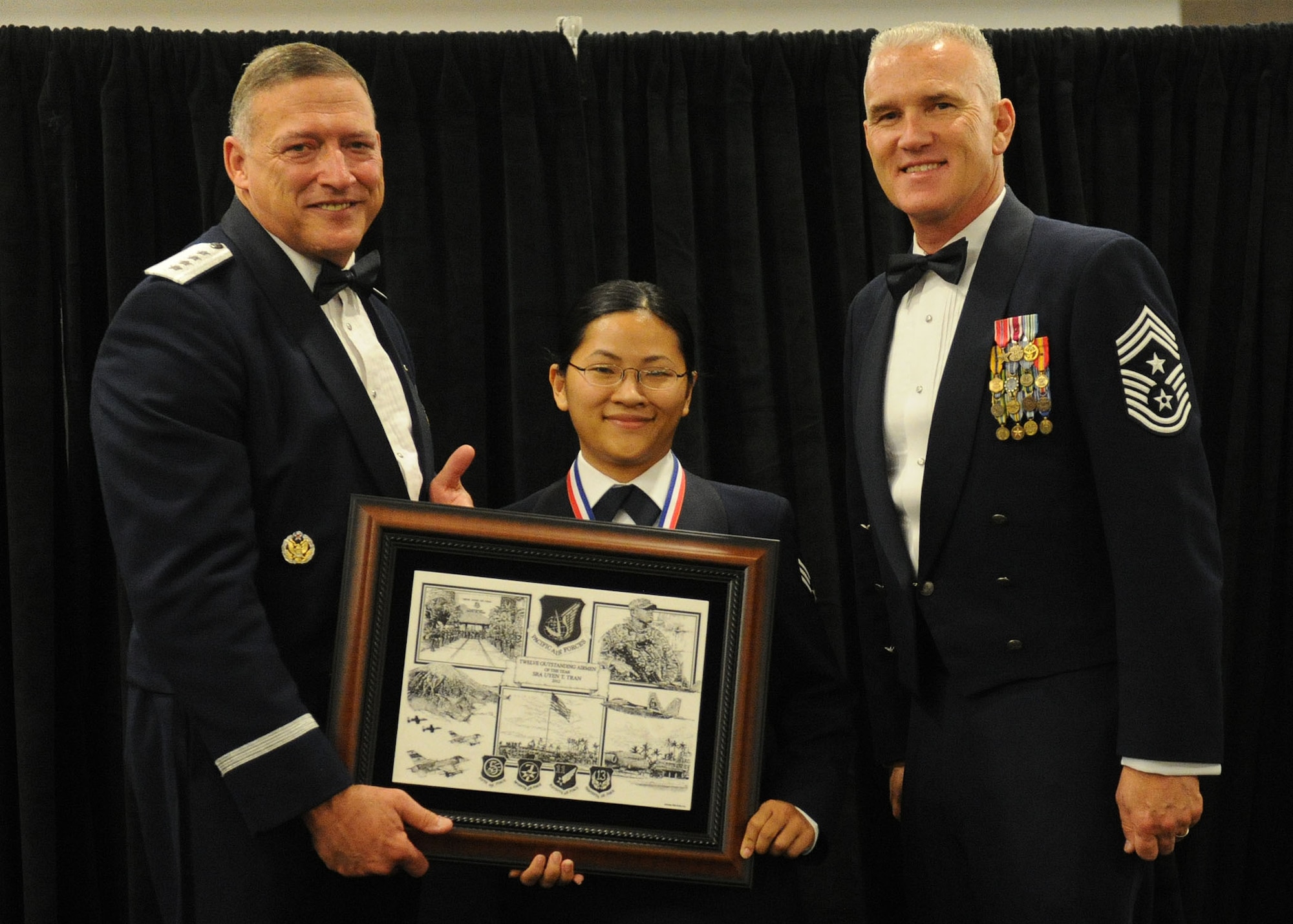Pacific Air Forces commander Gen. Gary North and Chief Master Sgt. Brooke McLean, PACAF command chief, present Senior Airman Uyen T. Tran, a material management journeyman from the 154th Logistics Readiness Squadron, Joint Base Pearl Harbor-Hickam, Hawaii, with PACAF Outstanding Airman of the Year honors at the Tradewinds Enlisted Club, JBPH-H, Hawaii, April 27, 2012. (U.S. Air Force photo/Tech. Sgt. Jerome S. Tayborn)