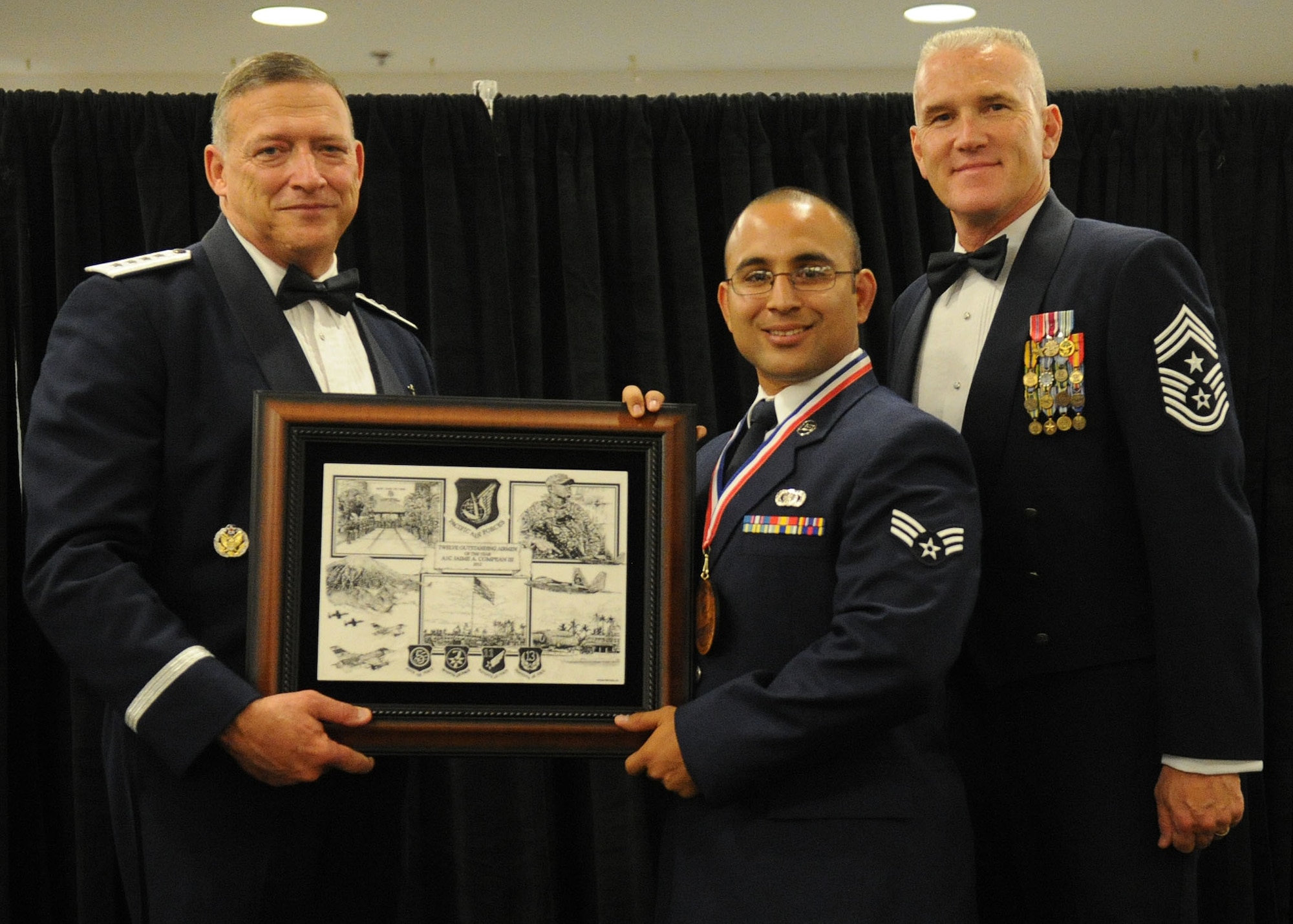 Pacific Air Forces commander Gen. Gary North and Chief Master Sgt. Brooke McLean, PACAF command chief, present Airman 1st Class Jaime A. Compean III, a contracting specialist from the 18th Contracting Squadron, Kadena Air Base, Japan, with PACAF Outstanding Airman of the Year honors at the Tradewinds Enlisted Club, Joint Base Pearl Harbor-Hickam, Hawaii, April 27, 2012. (U.S. Air Force photo/Tech. Sgt. Jerome S. Tayborn)