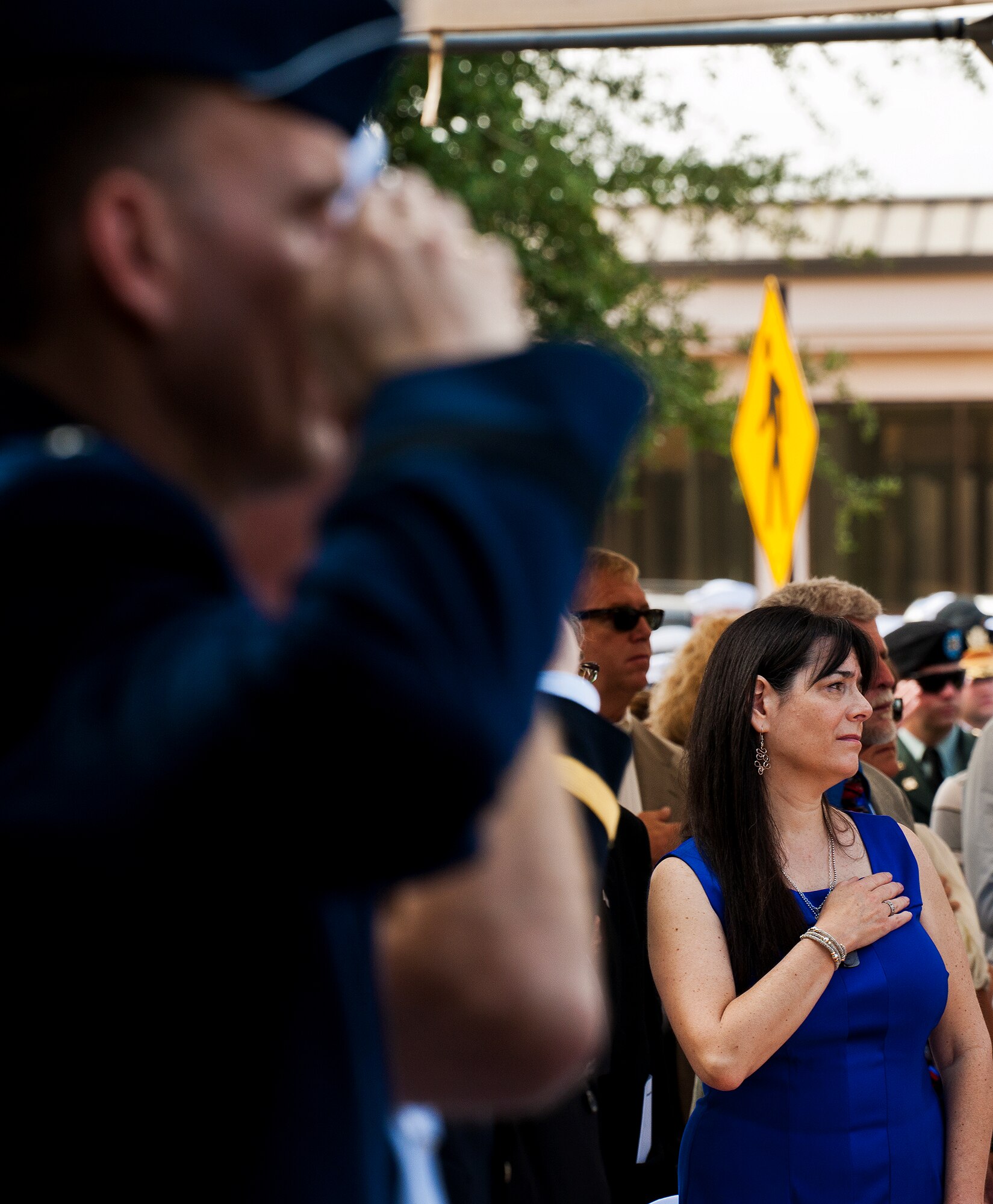 Lauren Seidler places her hand over her heart as military members salute during the national anthem at the Explosive Ordnance Disposal Memorial Ceremony to begin May 5, 2012, at Eglin Air Force Base, Fla.  Seidler’s son, Airman 1st Class Matthew Seidler, was one of five fallen EOD Airmen honored at the event.  (U.S. Air Force photo/Samuel King Jr.)