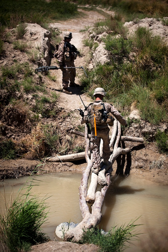 U.S. Marine Lance Cpl. Michael Straub, center,  uses a makeshift bridge to cross a canal under the watch of Lance Cpl. Andrew Loggins during a security patrol in the Durzay region of the Garmsir district of Helmand province, Afghanistan, April 30, 2012. The Marines are assigned to India Company, 3rd Battalion, 3rd Marine Regiment.