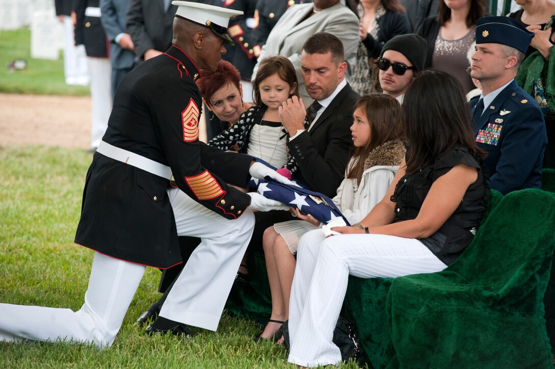 Sgt. Maj. Eric Stockton, Marine Barracks Washington sergeant major, presents a folded flag to Jennifer, 8, oldest daughter of Master Sgt. Scott E. Pruitt, a financial resource management analyst, during his funeral at Arlington National Cemetary May 8. Pruitt died from an improvised explosive device attack during combat maneuvers in Afghanistan, April 28. He was the first Marine in his job specialty to die in combat in Corps history.