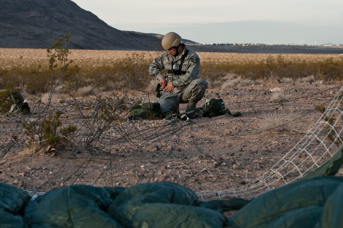 U.S. Air Force Tech. Sgt. Felipe Lucero, 820th RED HORSE airborne flight explosive ordinance disposal craftsman, untangles parachute lines after conducting a static line training jump from a Wyoming Air National Guard C-130 Hercules April 26, 2012, at Nellis Air Force Base, Nev. The primary purpose of RED HORSE EOD is clearing unexploded ordinance before repair of damaged airfields begins. (U.S. Air Force photo by Airman 1st Class Jason Couillard)