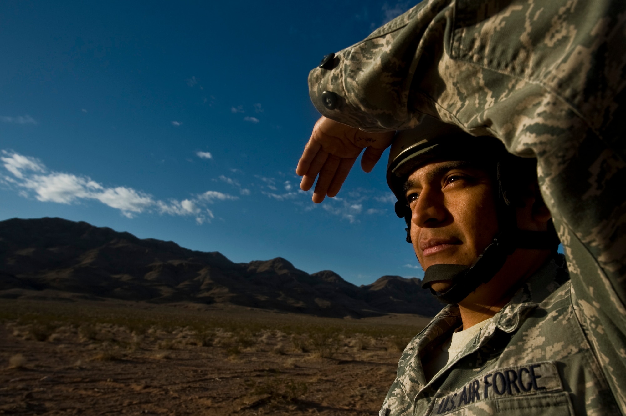 U.S. Air Force Staff Sgt. Omar Torres, 820th RED HORSE Squadron airborne flight member,  looks through the rising sun to locate a Wyoming Air National Guard C-130 Hercules, during a training mission, April 26, 2012, at Nellis Air Force Base, Nev. Torres had to locate the C-130 for wind readings and to monitor the jump. (U.S. Air Force photo by Airman 1st Class Daniel Hughes)

