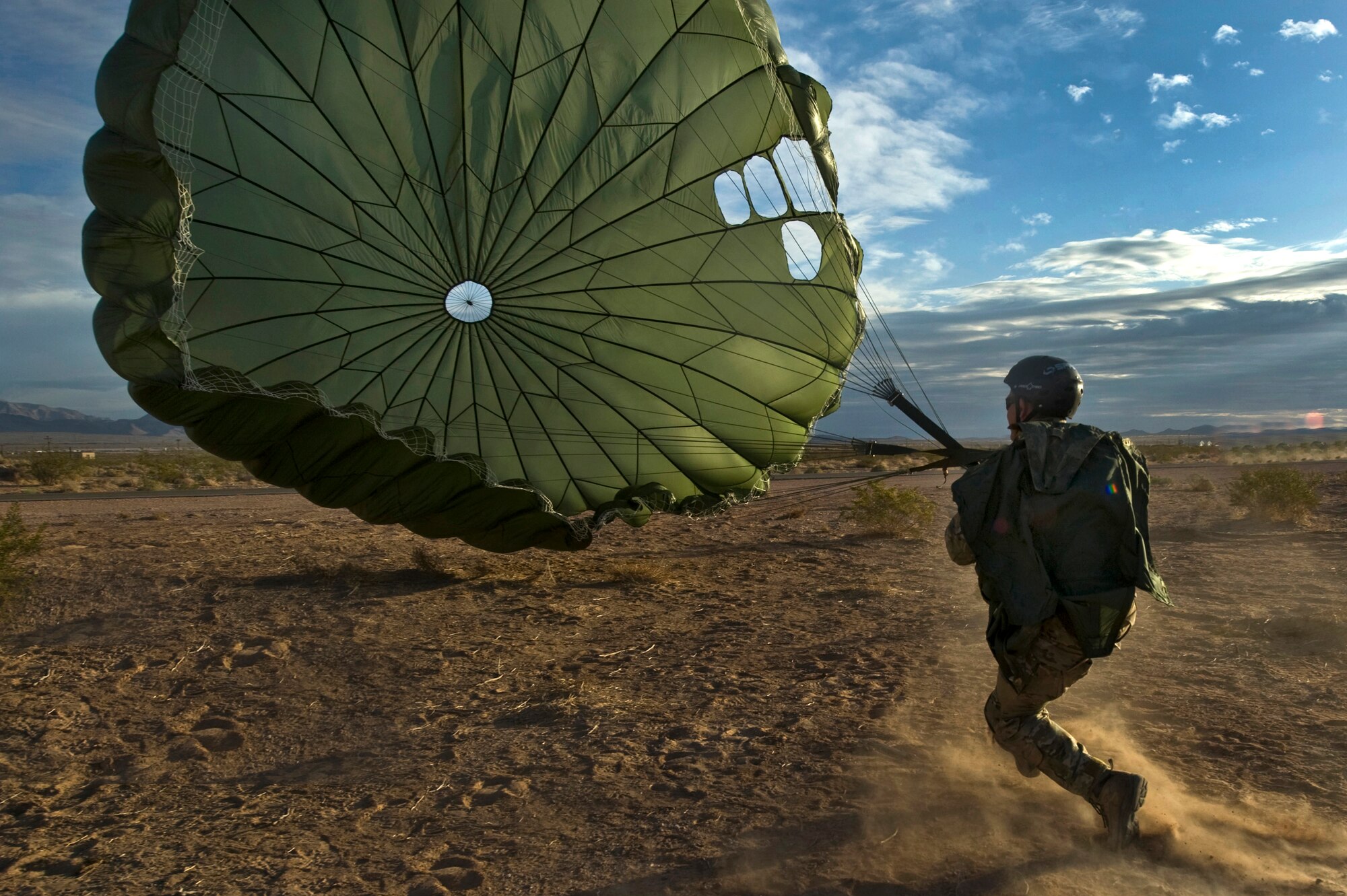 A U.S. Air Force Joint Terminal Attack Controller gets pulled by his parachute after landing during a training mission, April 26, 2012, at Nellis Air Force Base, Nev. A static line parachute allows jumps from very low altitudes since the chute opens immediately after the jumper leaves the aircraft. (U.S. Air Force photo by Airman 1st Class Daniel Hughes)
