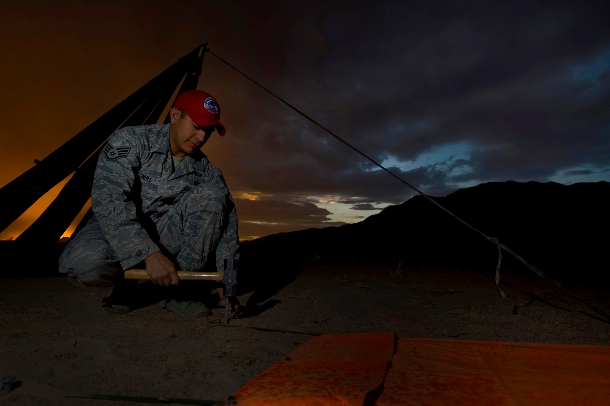 U.S. Air Force Staff Sgt. Omar Torres, 820th RED HORSE Squadron airborne flight member,  stakes down tarps marking the designated landing zone during a training mission, April 26, 2012, at Nellis Air Force Base, Nev. Torres is getting certified as a DLZ safety officer. (U.S. Air Force photo by Airman 1st Class Daniel Hughes)