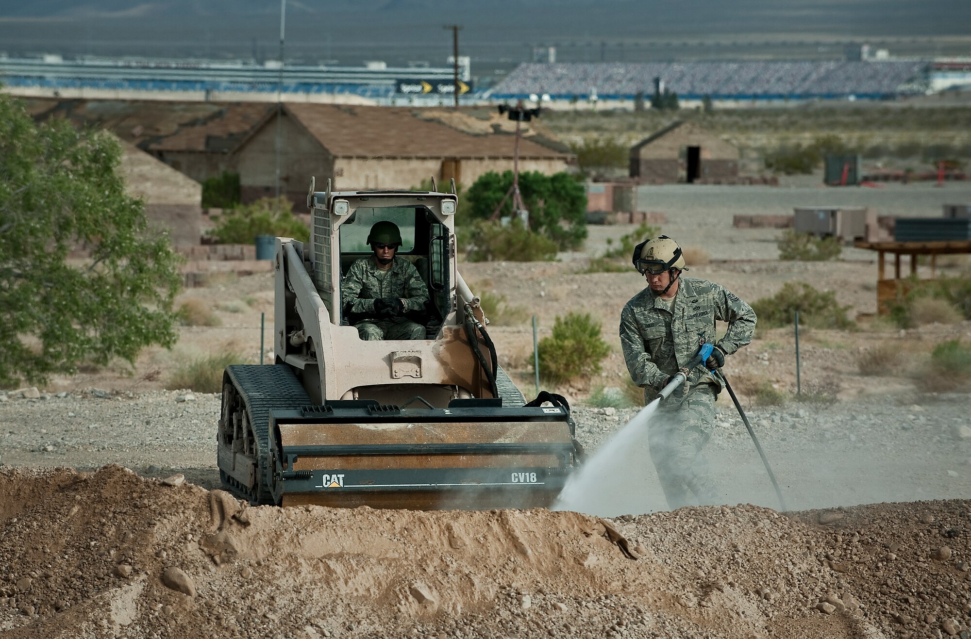 U.S. Air Force Tech Sgt. Joshua Tully, 820th RED HORSE Squadron airborne flight fire fighter, waters down dirt as Staff Sgt. Norris, 820th RED HORSE Squadron airborne flight pavements and construction craftsman, waits to level it down during a training mission on a simulated runway April 26, 2012, at Nellis Air Force Base, Nev. The RED HORSE Engineering Team assesses airfields, clears obstacles, makes expedient airfield damage repairs, and provides initial assessment of required follow-on forces and material resources to establish sustainable contingency airfield operations. (U.S. Air Force photo by Staff Sgt. Christopher Hubenthal)
