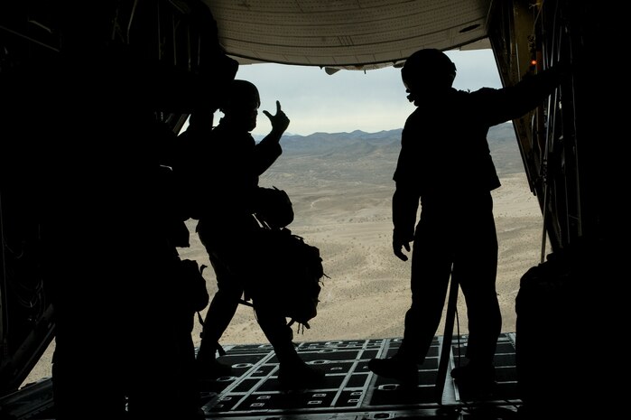 U.S. Air Force Tech. Sergeant Romag, 820th RED HORSE Squadron airborne flight jump master, signals to Airmen during a sling load training jump from a Wyoming Air National Guard C-130 Hercules April 24, 2012, at Nellis Air Force Base, Nev. The jumpmaster's responsibilities consist of getting paratroopers trained properly, getting them to the aircraft, and getting them safely delivered to the ground. (U.S. Air Force photo by Staff Sgt. Christopher Hubenthal)