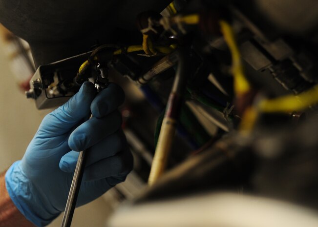 Tim Goreman tightens a wire clamp on a C-17 Globemaster III engine at the Joint Base Charleston – Air Base C-17 engine shop May 2. The wire is connected to ensure temperature is regulated in the engine. Goreman is an aviation maintenance technician with United Airlines. (U.S. Air Force photo/Staff Sergeant Katie Gieratz)