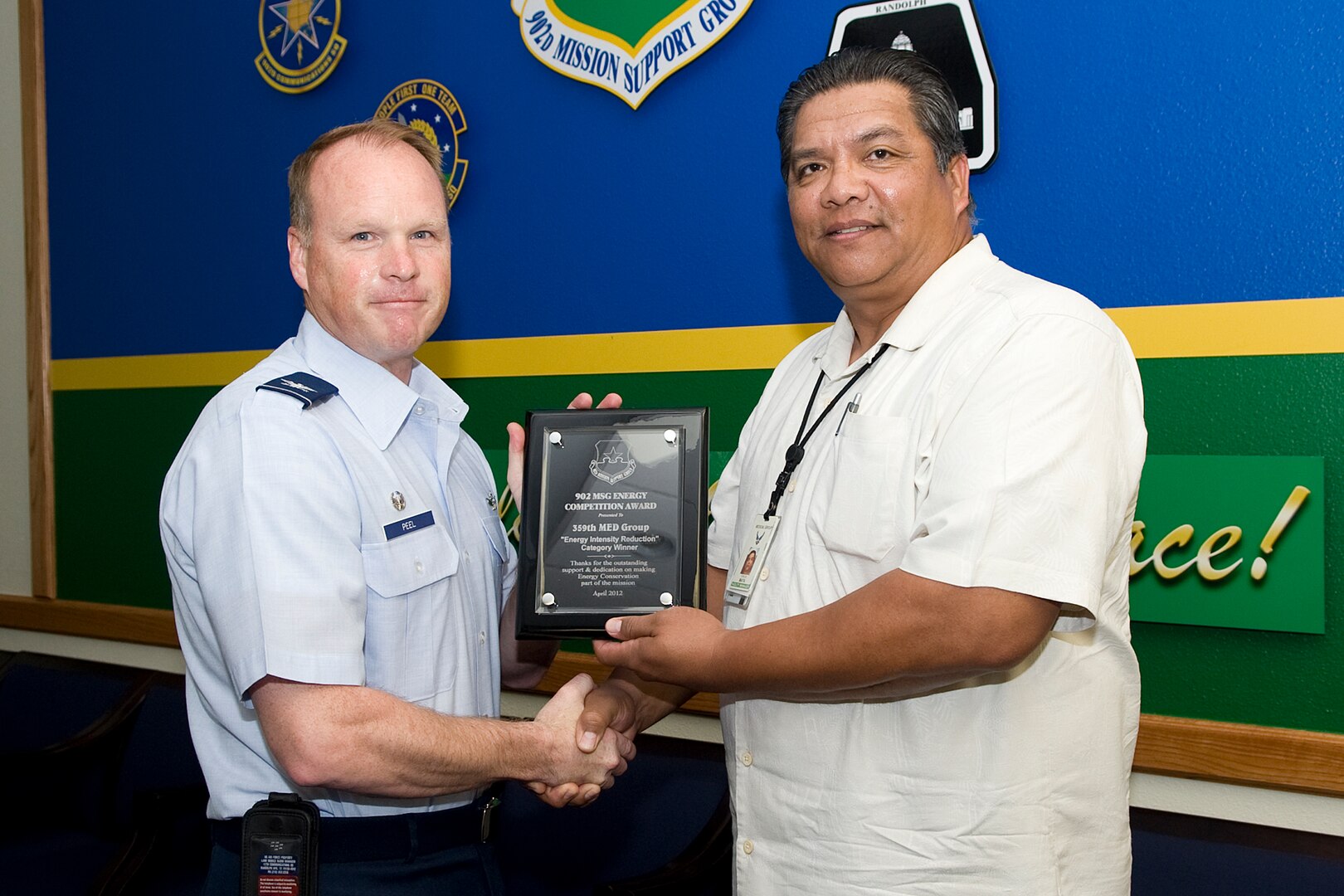 Carlos Mata, 359th Medical Group facility manger, receives the energy intensity reduction award from Col. Scott Peel, 902nd Mission Support Group commander, May 7 concluding a base-wide energy conservation competition at Joint Base San Antonio-Randolph, Texas . (U.S. Air Force photo by Benjamin Faske)