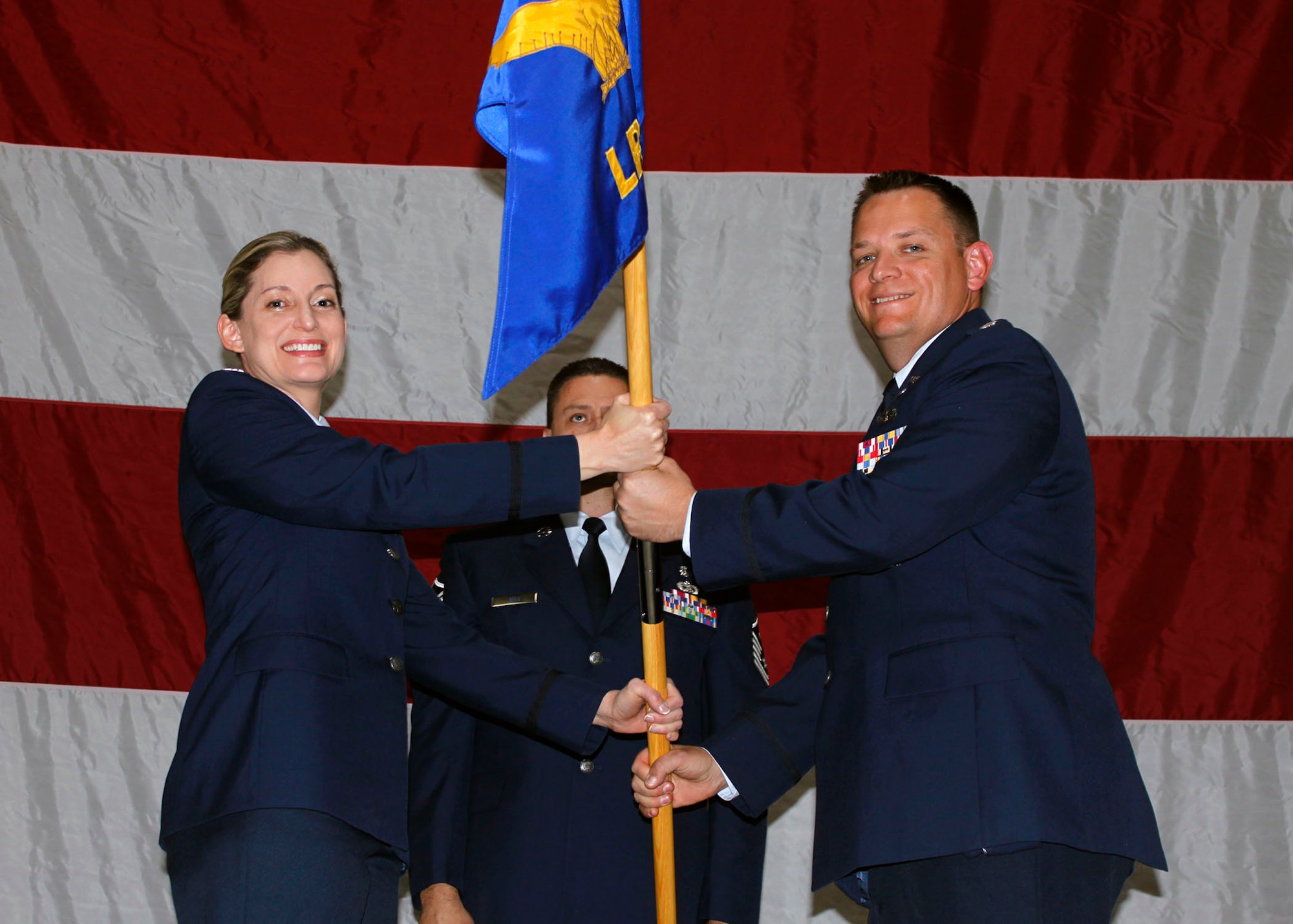 Col. Anne Gunter, commander, 944th Mission Support Group hands squadron command of the 944th Logistics Readiness Squadron to Lt. Col. Kip Schlum, during a change-of-command ceremony held here May 6. (U.S. Air Force Photo by Tech. Sgt. Meredith Mingledorff) 
