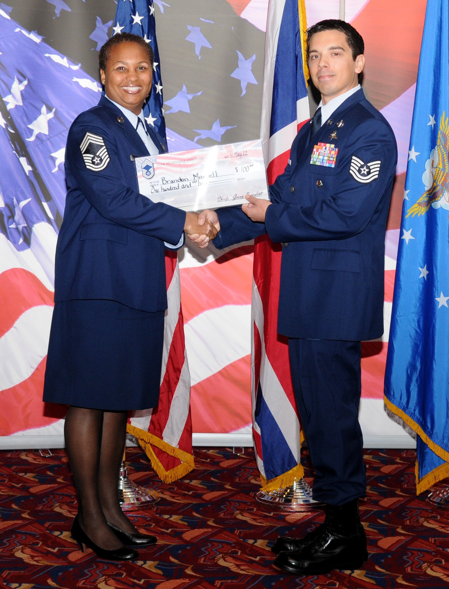 RAF MILDENHALL, England – Chief Master Sgt. Vernitia Johnson, 100th Logistics Readiness Squadron, presents Tech. Sgt. Brandon Maxwell, 321st Special Tactics Squadron, with a check for $100 on behalf of the Team Mildenhall Chief’s Group at the Community College of the Air Force commencement ceremony May 4 at the Galaxy Club here. The money will be used towards future education expenses. (U.S. Air Force photo/Senior Airman Rachel Waller)