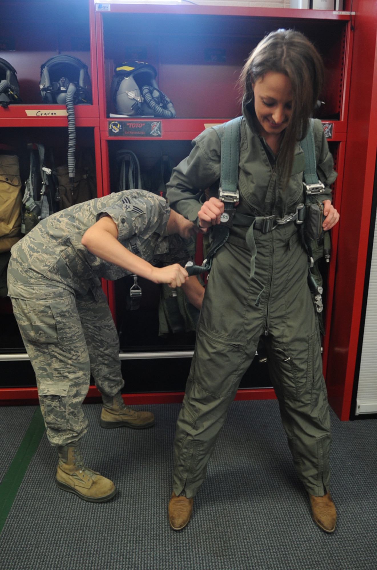 U.S. Air Force Senior Airman Angela Tobin assists Kristin Rhynehart with securing her harness during flight gear fitting on Seymour Johnson Air Force Base, N.C., May 4, 2012. Spouses of 333rd Fighter Squadron and Aircraft Maintenance Unit Airmen were given the opportunity to partake in a taxi ride in thanks for their support. Tobin, 4th Operations Support Squadron aircrew flight equipment journeyman, hails from Moreno Valley, Calif. Rhynehart is the spouse of Staff Sgt. Jared Rhynehart, 333rd AMU crew chief, and hails from Greenville, N.C. (U.S. Air Force photo/Airman 1st Class Aubrey Robinson/Released)