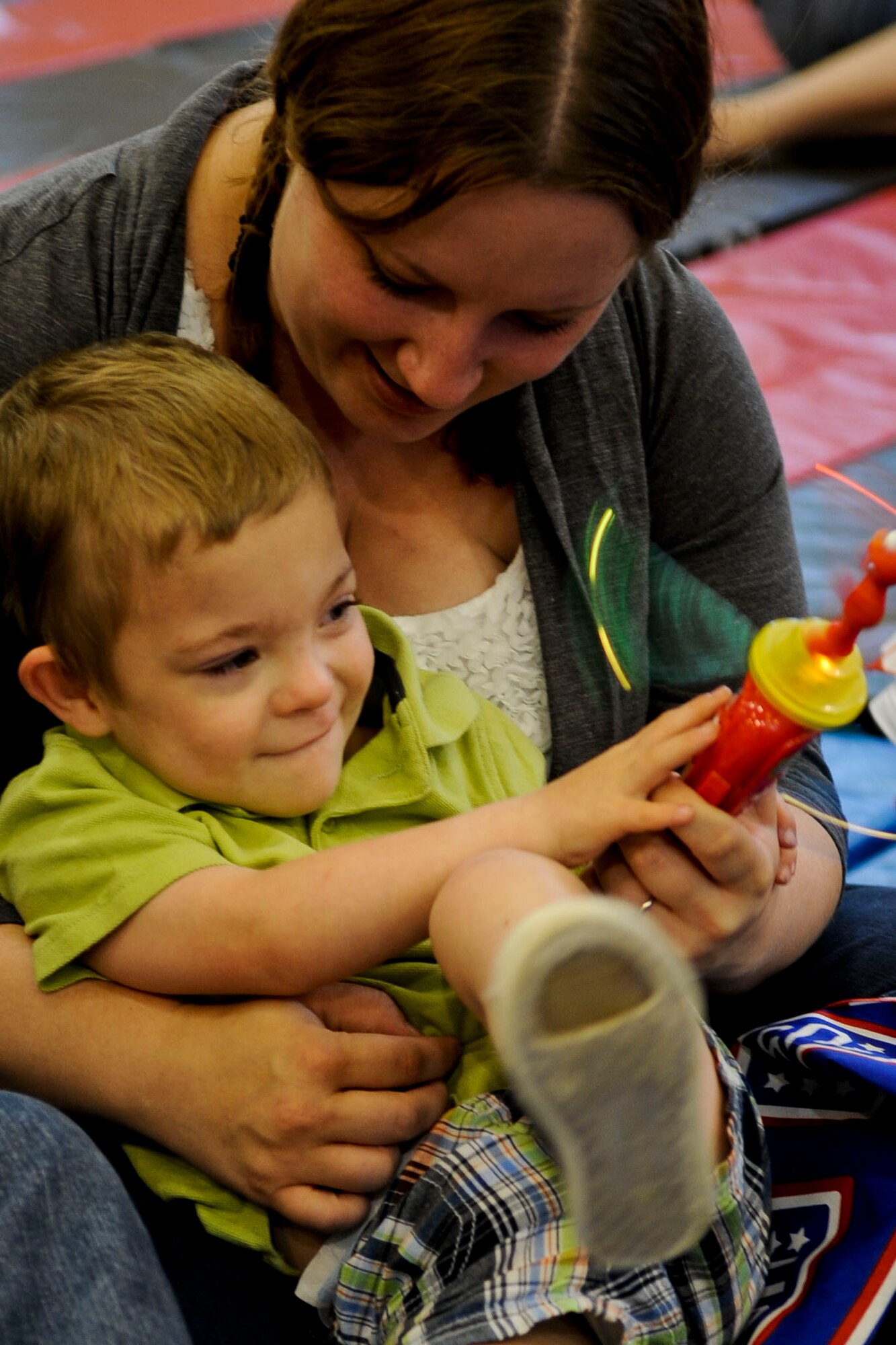 Three-year-old Edward Menken plays with an Elmo toy on the lap of his mother, Misty Menken, prior to the start of the 2011 Joining Forces: Sesame Street and USO Special Event show at the Langley Air Force Base, Va., youth center, May 7, 2012. The show featured several popular Sesame Street characters, and dealt with topics specifically relating to military families.  (U.S. Air Force photo by Senior Airman Wesley Farnsworth/Released) 