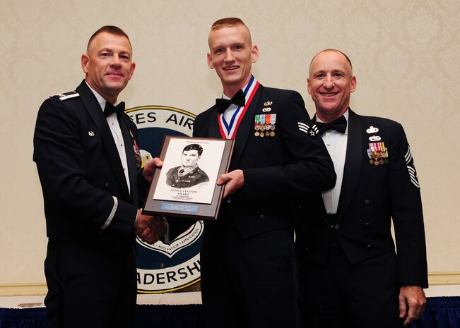Col. Richard McComb and Chief Master Sgt. Earl Hannon present the John L. Levitow Award to Senior Airman Patrick Dougherty during the Airman Leadership School Class graduation May 4 at Joint Base Charleston - Air Base. The Levitow award is given for a student's exemplary demonstration of excellence, both as a leader and a scholar. McComb is the JB Charleston commander and Hannon is the JB Charleston command chief. Dougherty is a 628th Civil Engineer Squadron explosive ordnance disposal journeyman. (U.S. Air Force photo/Staff Sgt. Katie Gieratz) 
