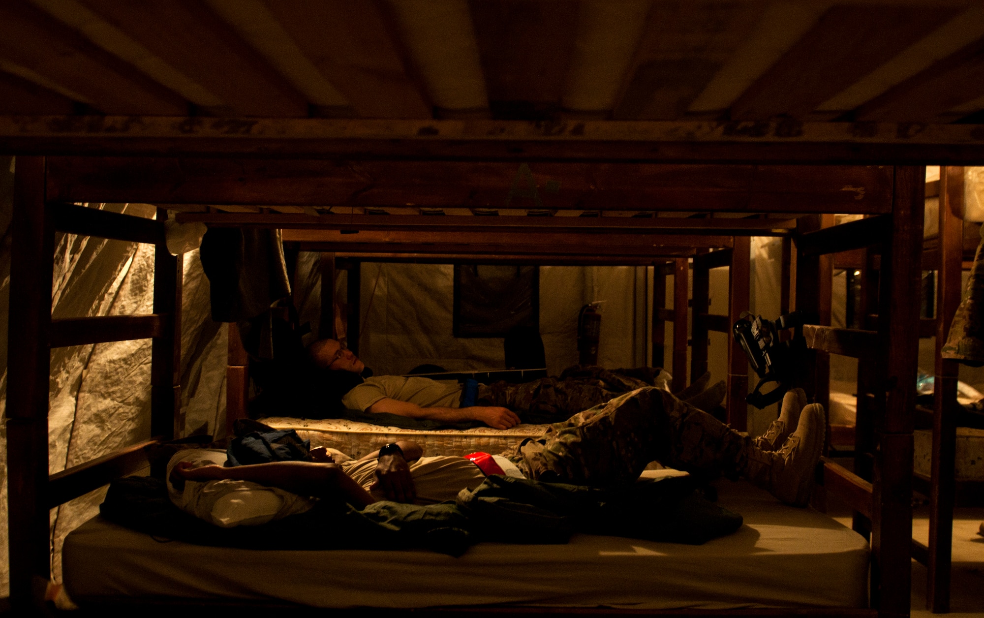 From close to far, Airmen 1st Class Ryan Persaud and Lee Heerspink, members of the U.S. Air Forces Central Band Nightwing, try to catch up on a few minutes of sleep May 2, 2012 at Kandahar Airfield Afghanistan. While on the road, the band often plays late into the night. (U.S. Air Force photo by Staff Sgt. David Salanitri/Released)