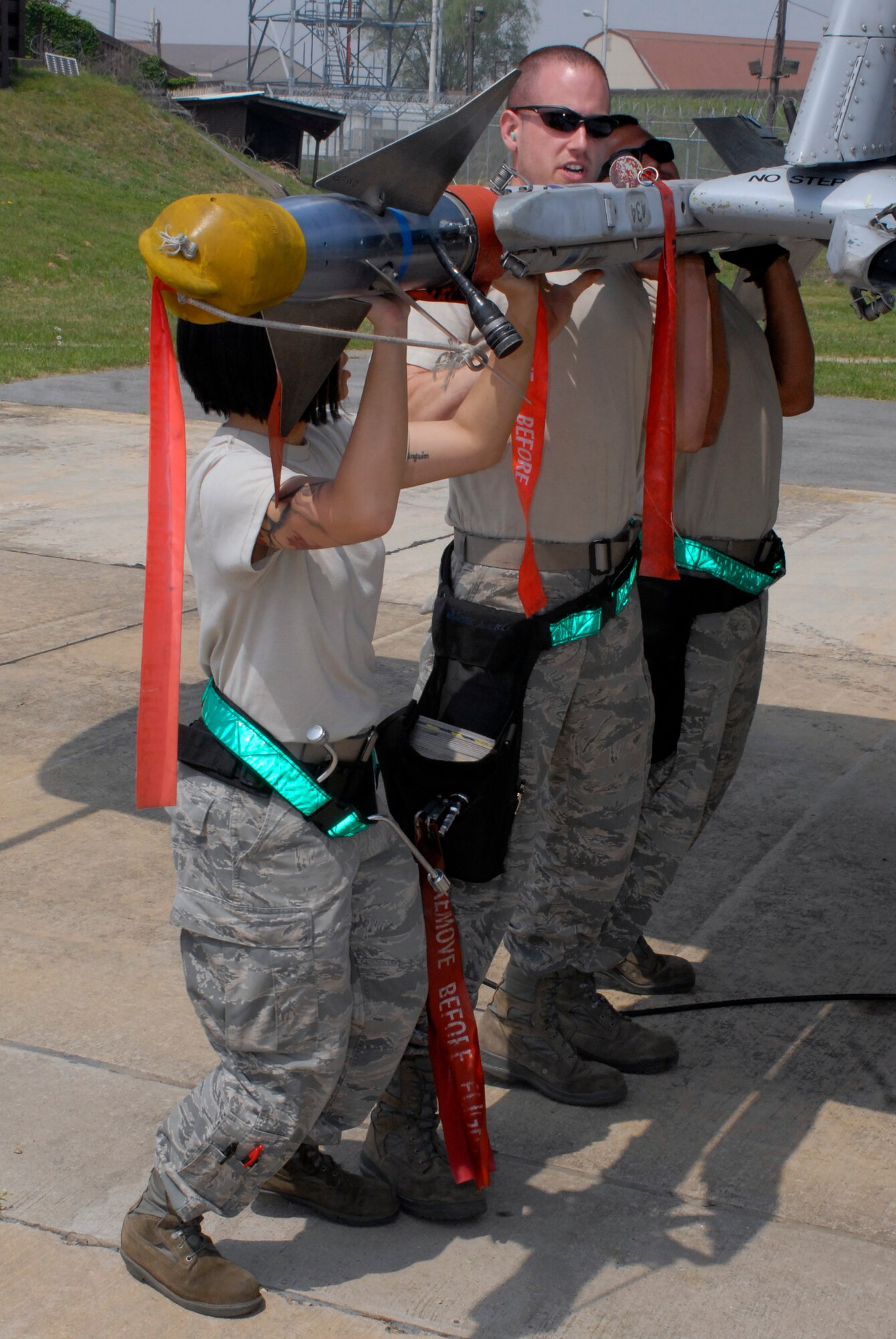 (From left to right) Airman 1st Class Cynthia Frias, Staff Sgt. Joshua Stone, and Senior Airman Daniel Jimenez, 25th Aircraft Maintenance Unit weapon loaders, lift an AIM-9 missile into position during a weapons loading competition at Osan Air Base, Republic of Korea, May 5, 2012. (U.S. Air Force photo/Tech. Sgt. Eric Petosky)