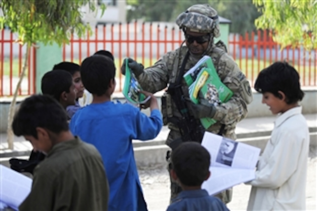 U.S. Army Sgt. 1st Class Carl Coles hands out magazines while greeting children and other members of the community during a mission in Afghanistan's Farah province, May 8, 2012. Coles is a civil affairs soldier assigned to Provincial Reconstruction Team Farah.