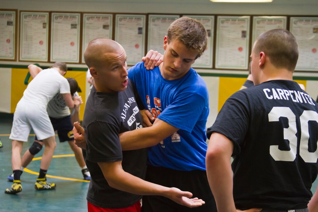 Corporal Bobby Phelps, an infantryman and member of the All Marine Wrestling Team explains proper Greco-Roman wrestling technique to young wrestlers participating in the Marine led clinic at St. Edward High School, May 9. Members of the elite All Marine Wrestling Team had the opportunity to share some of their skills and knowledge with over 60 Cleveland area youth during the two day clinic.