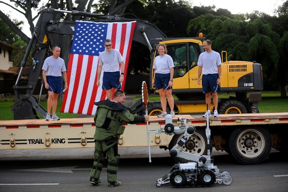 Senior Airman Wes McCrannie, 647th Civil Engineer Squadron explosive ordnance disposal flight, takes the Warrior Stick from an EOD robot and hands it to Col. Michael Novotny, 15th Wing Maintenance Group commander, to conclude of the two-mile Team Hickam Warrior Run May 3, at Joint Base Pearl Harbor-Hickam, Hawaii. This event was sponsored by the 647th CES and their Prime BEEF Airmen. Prime BEEF, is a Prime Base Engineer Emergency Force is a rapidly deployable, specialized civil engineer unit of the Air Force Prime BEEFs provide a full range of engineering support required to establish, operate, and maintain garrison and contingency air bases. The robot was driven by Senior Airman Benjamin Hancock. (U.S. Air Force photo/Staff Sgt. Mike Meares)